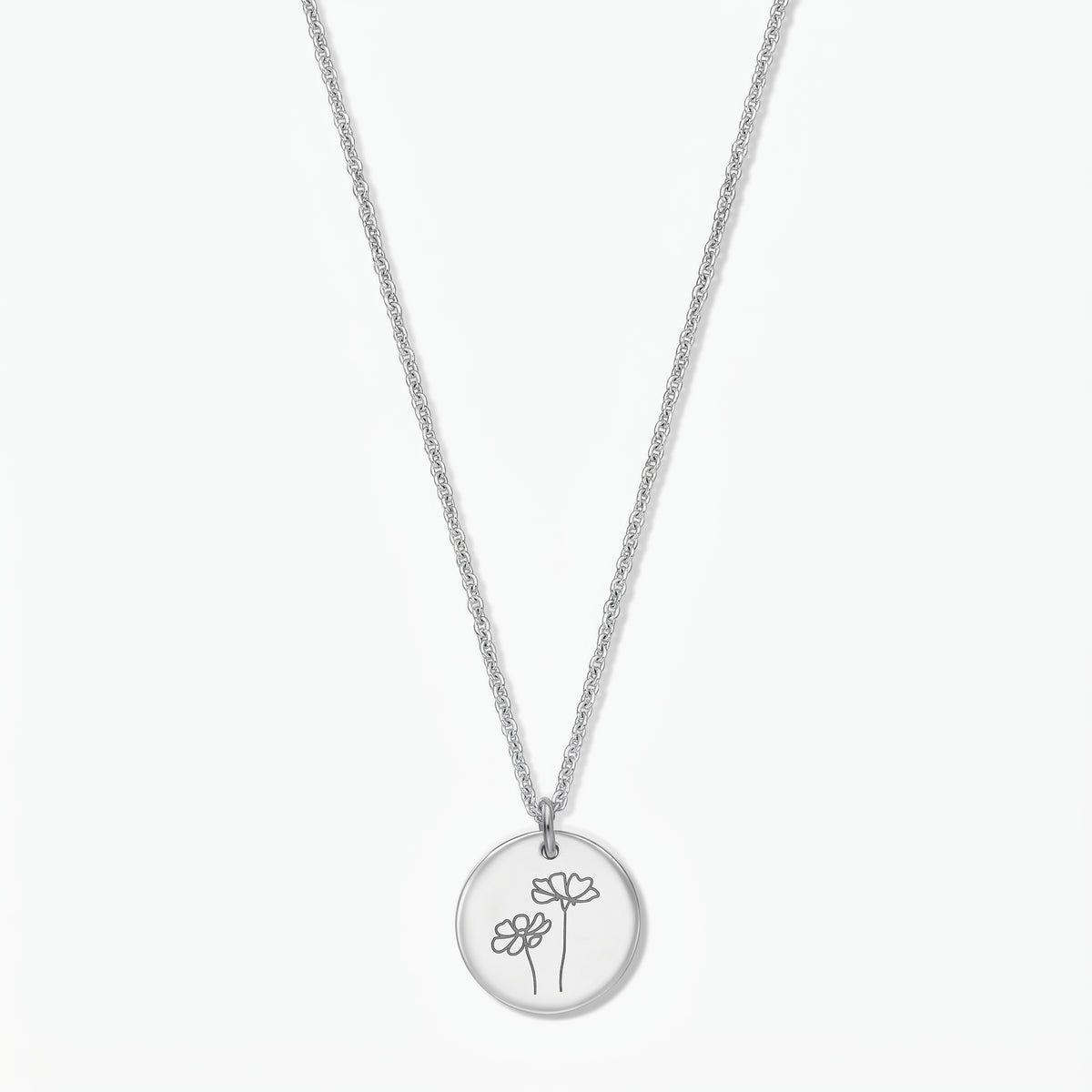 Collier fleur de naissance en argent sterling pour octobre (cosmos) par Indira, avec un pendentif disque rond gravé de deux fleurs de cosmos sur une fine chaîne en argent, isolé sur fond blanc.