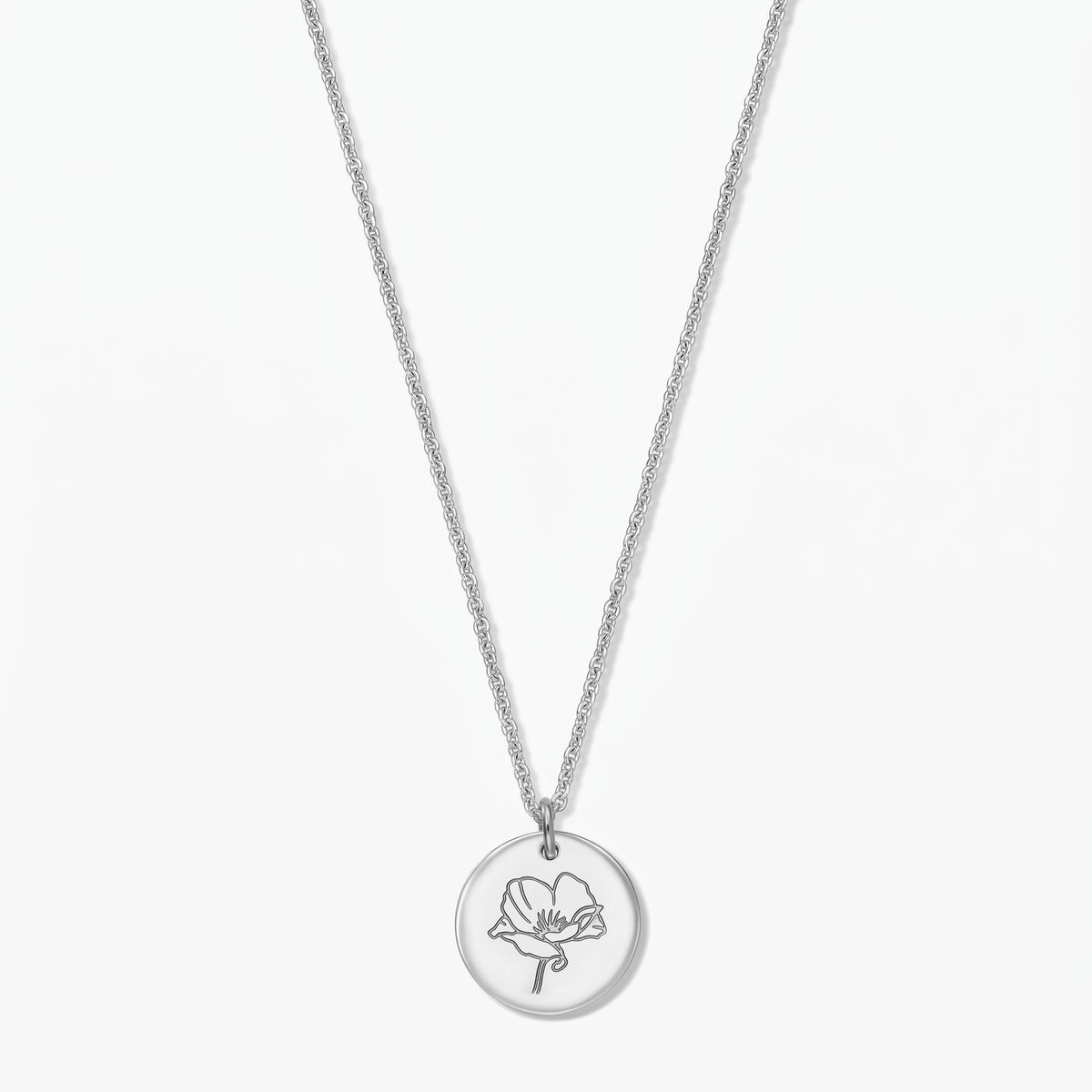 Collier fleur de naissance en argent sterling avec pendentif disque rond gravé d’un coquelicot, présenté au centre sur fond blanc.