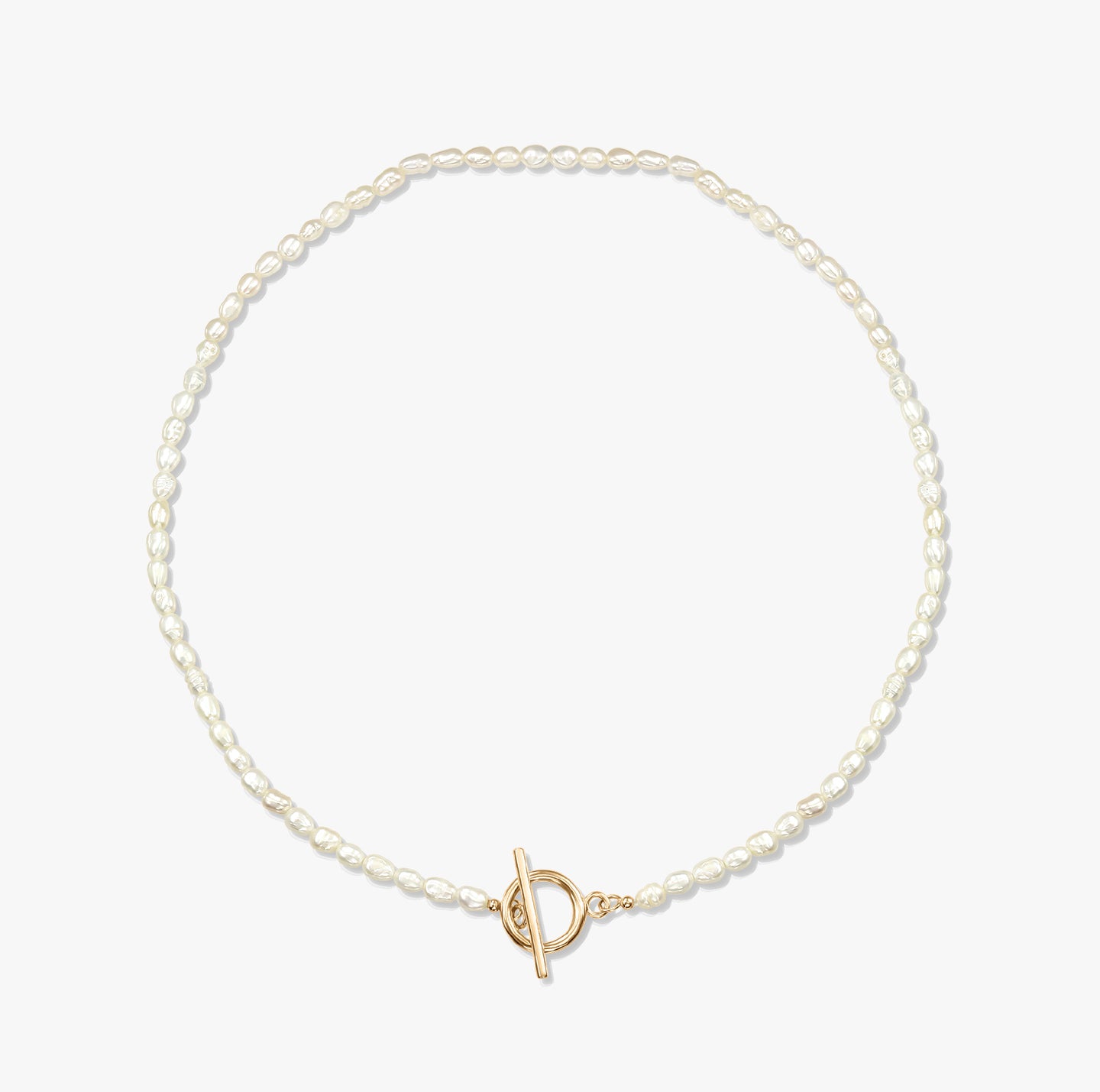 Un collier de perles minimaliste avec un fermoir toggle en or sur fond blanc.