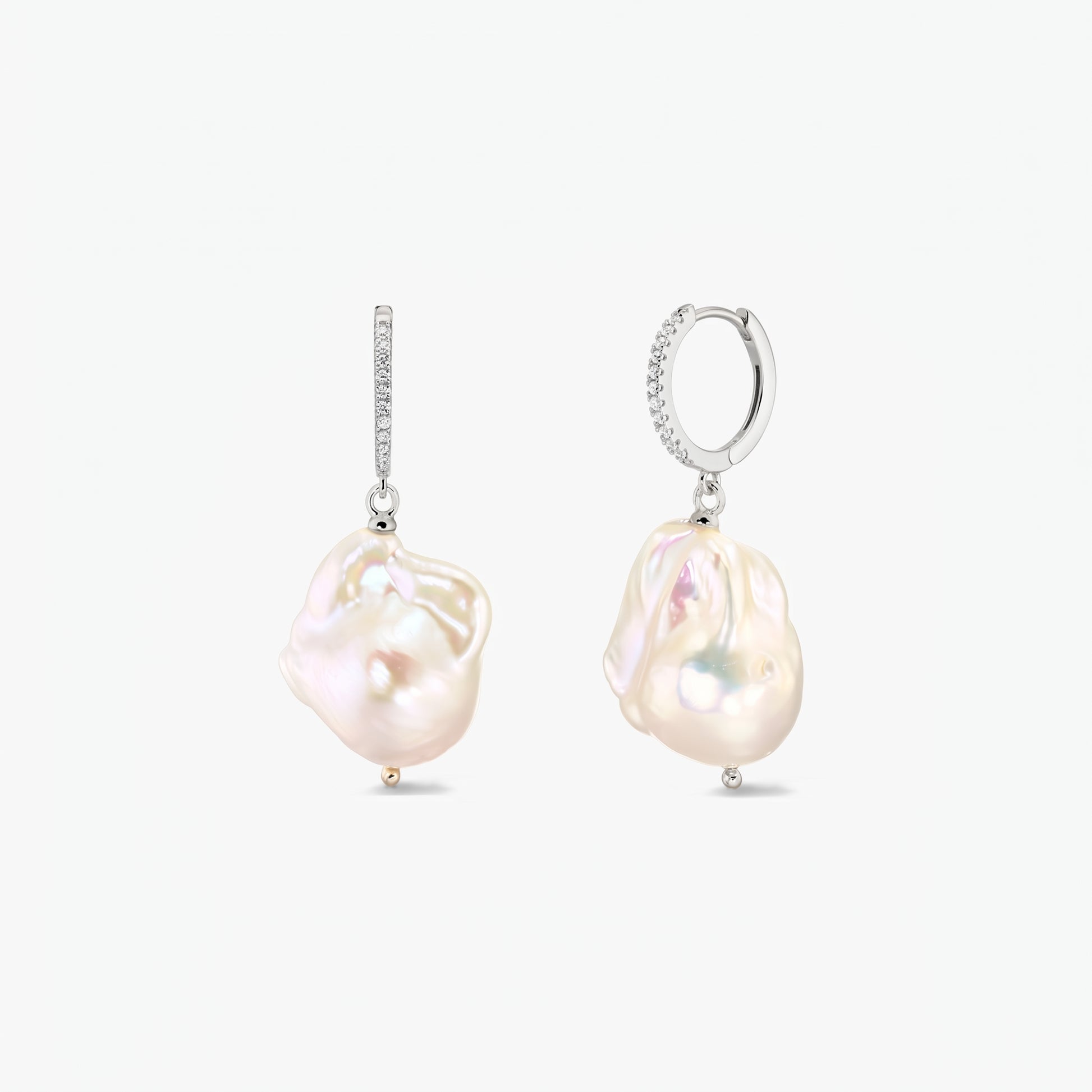 Paire de créoles en argent 925 rhodié, serties de zirconias en pavé et ornées de grandes perles baroques organiques, sur fond blanc.