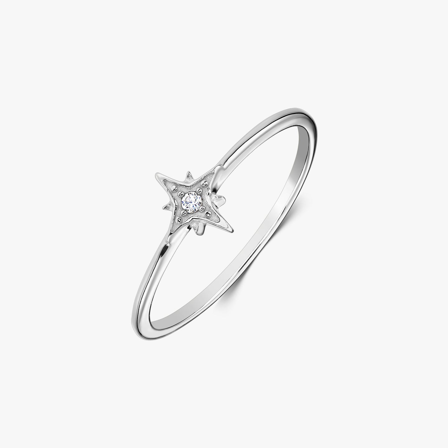 Bague fine en argent sterling avec un serti en forme d’étoile tenant une pierre en oxyde de zirconium blanc, photographiée sur fond blanc.