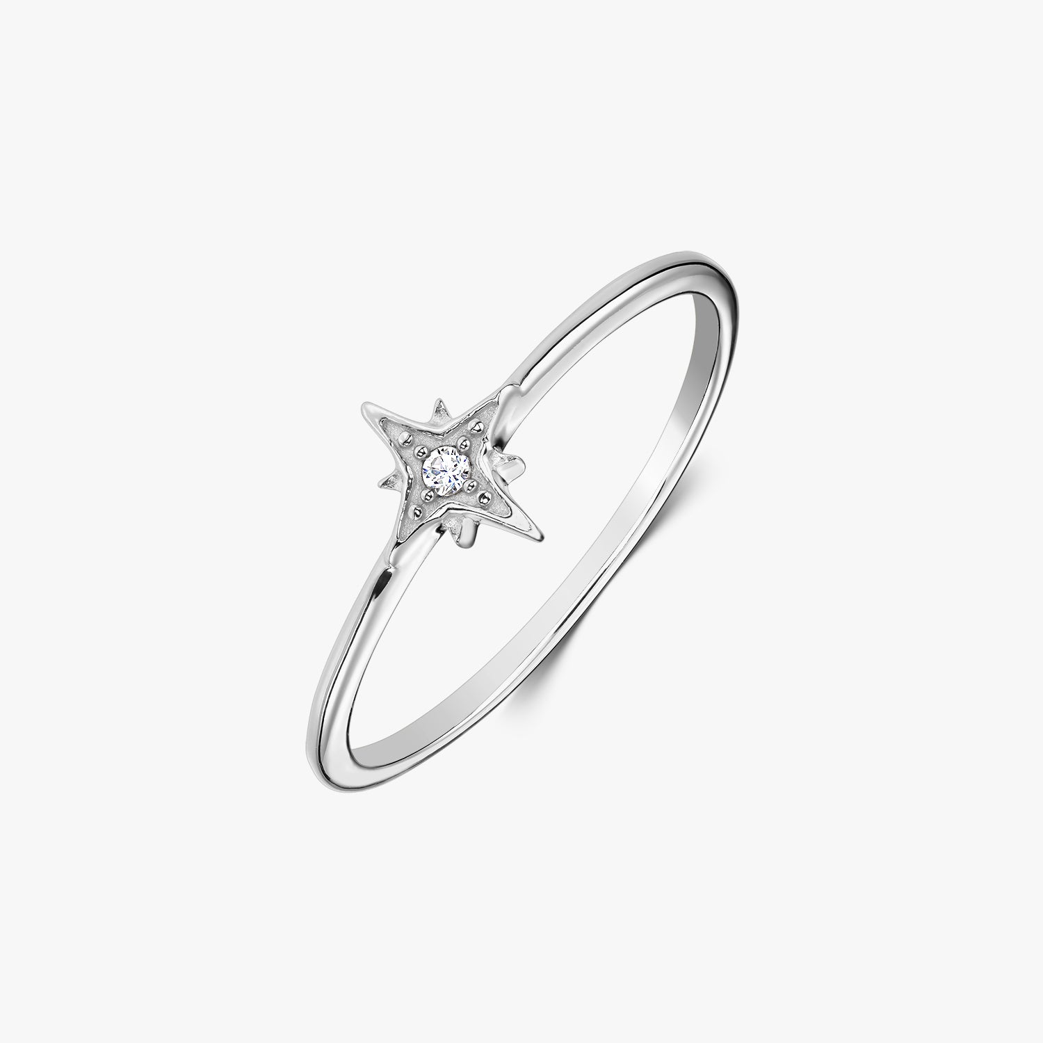 Bague fine en argent sterling avec un serti en forme d’étoile tenant une pierre en oxyde de zirconium blanc, photographiée sur fond blanc.