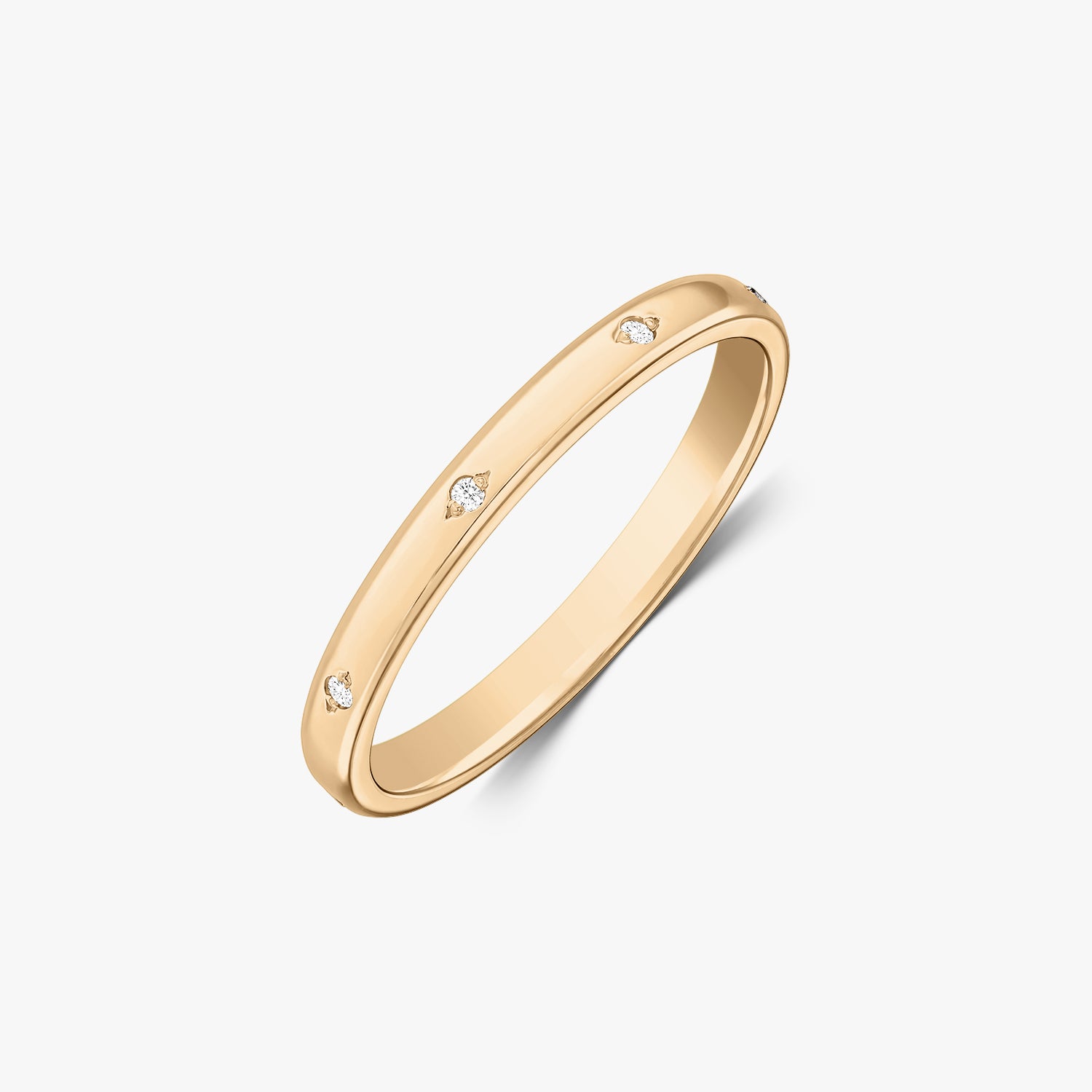Photo de studio en angle d’une alliance fine en or jaune 14K ornée de petits diamants sertis à fleur, sur fond blanc.