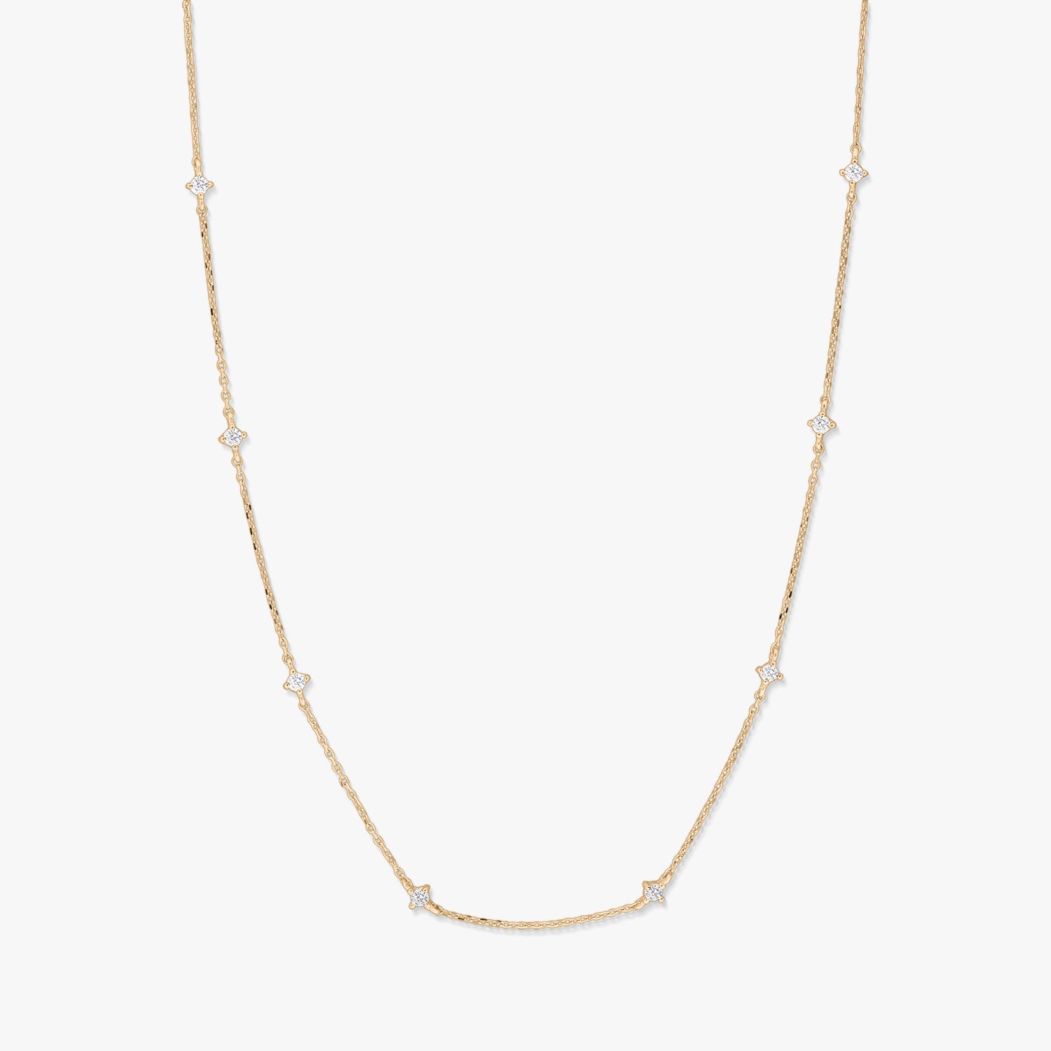 Delicate 14K yellow gold station necklace with small starburst-shaped white zirconia accents spaced along a fine chain, photographed on a white background.