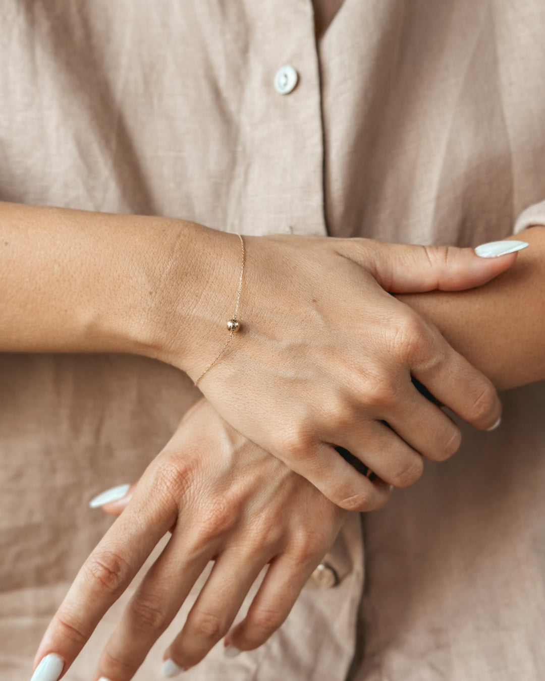 Gros plan sur les mains d'une personne portant un délicat bracelet en or.