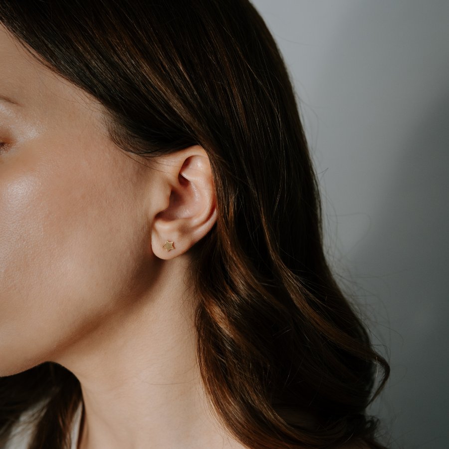 Gros plan sur une oreille de femme portant une boucle d'oreille étoile en or 14K.