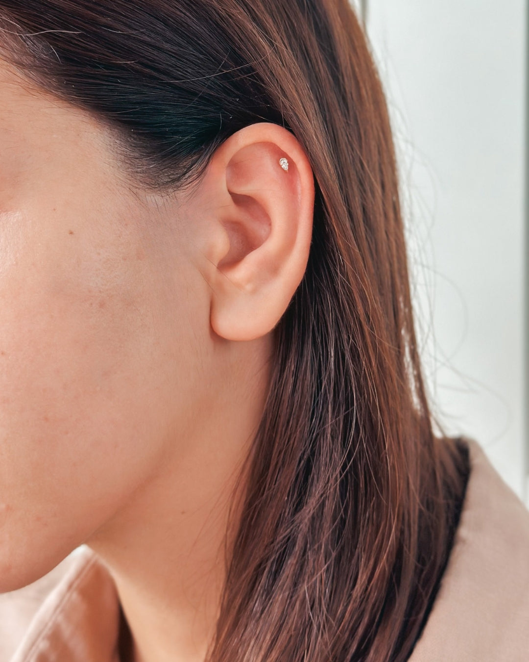 Gros plan d'une oreille avec une petite boucle d'oreille clou