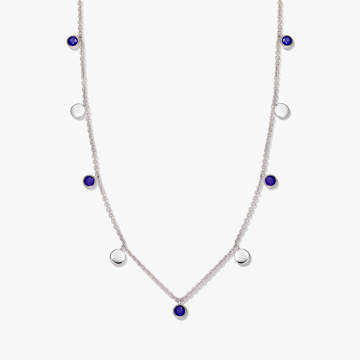Collier à stations en argent sterling avec cabochons ronds en lapis-lazuli et pastilles en argent poli sur fond blanc.