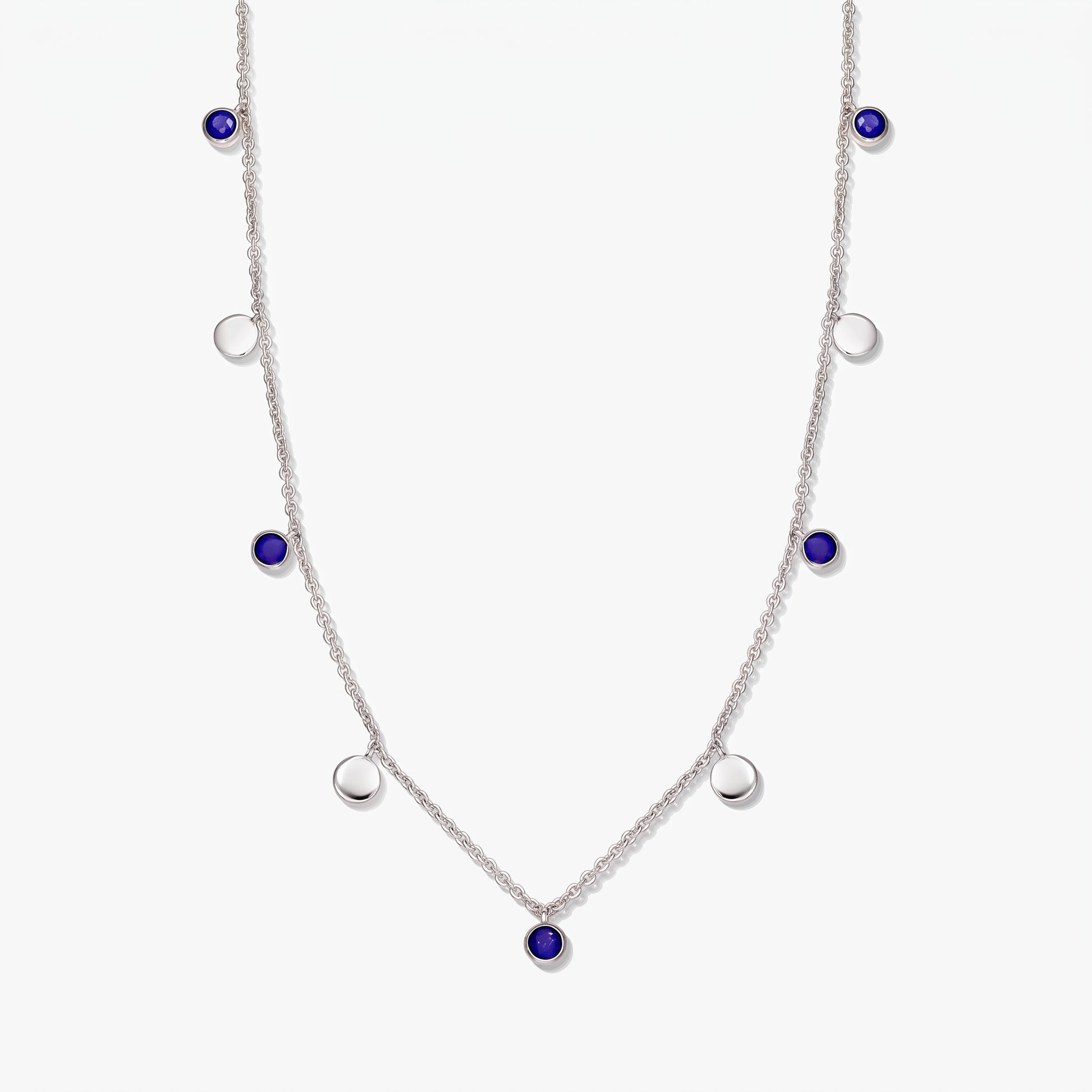 Collier à stations en argent sterling avec cabochons ronds en lapis-lazuli et pastilles en argent poli sur fond blanc.