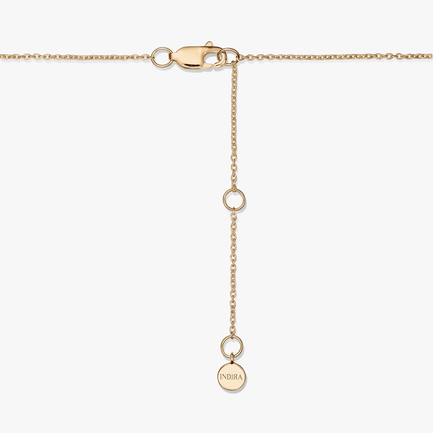 Gros plan d’un fermoir de collier en argent sterling plaqué or avec une chaînette d’extension réglable et un petit médaillon rond gravé « INDIRA », sur fond blanc.