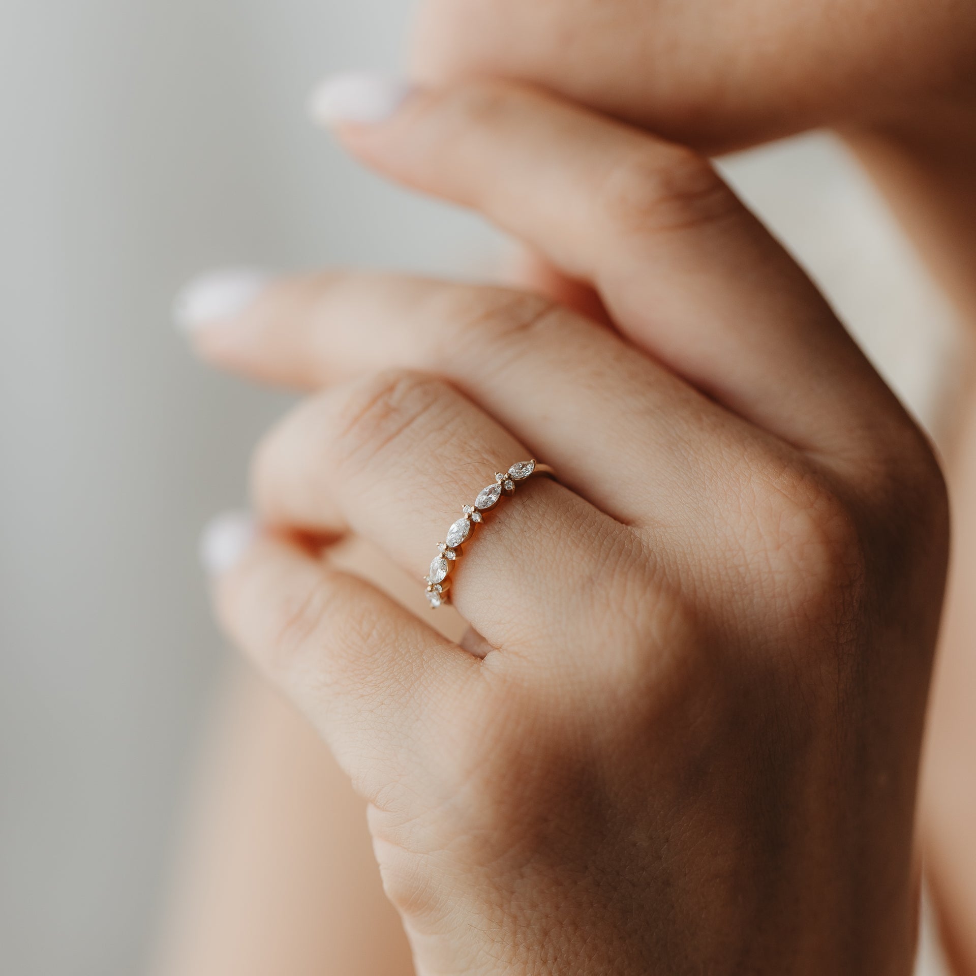 Gros plan d'une main portant la bague Fiorelle en or jaune sertie de diamants, alternant tailles marquise et ronde.