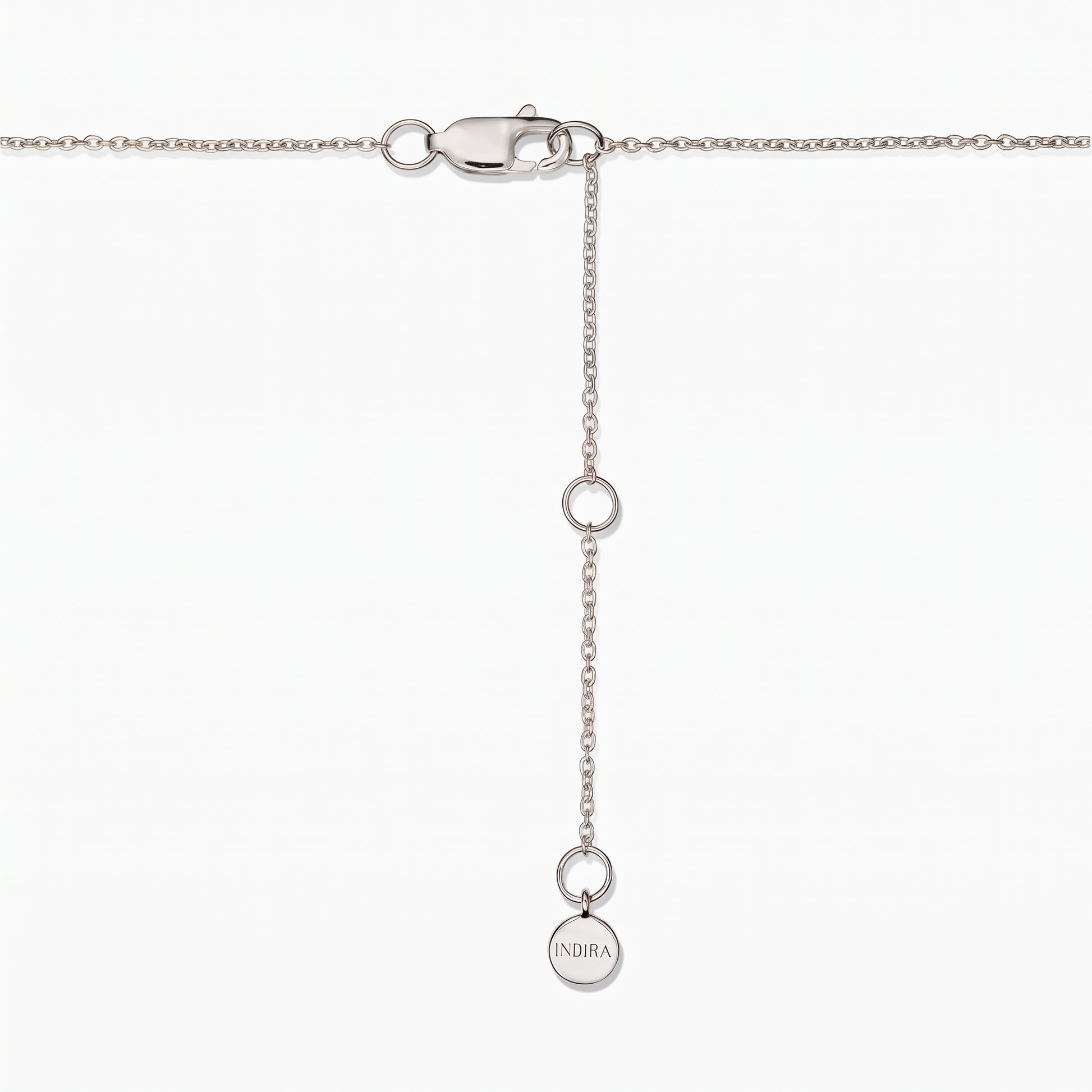 Gros plan sur le fermoir d'un collier en argent sterling avec chaîne d'extension réglable et une petite pastille ronde Indira, sur fond blanc.