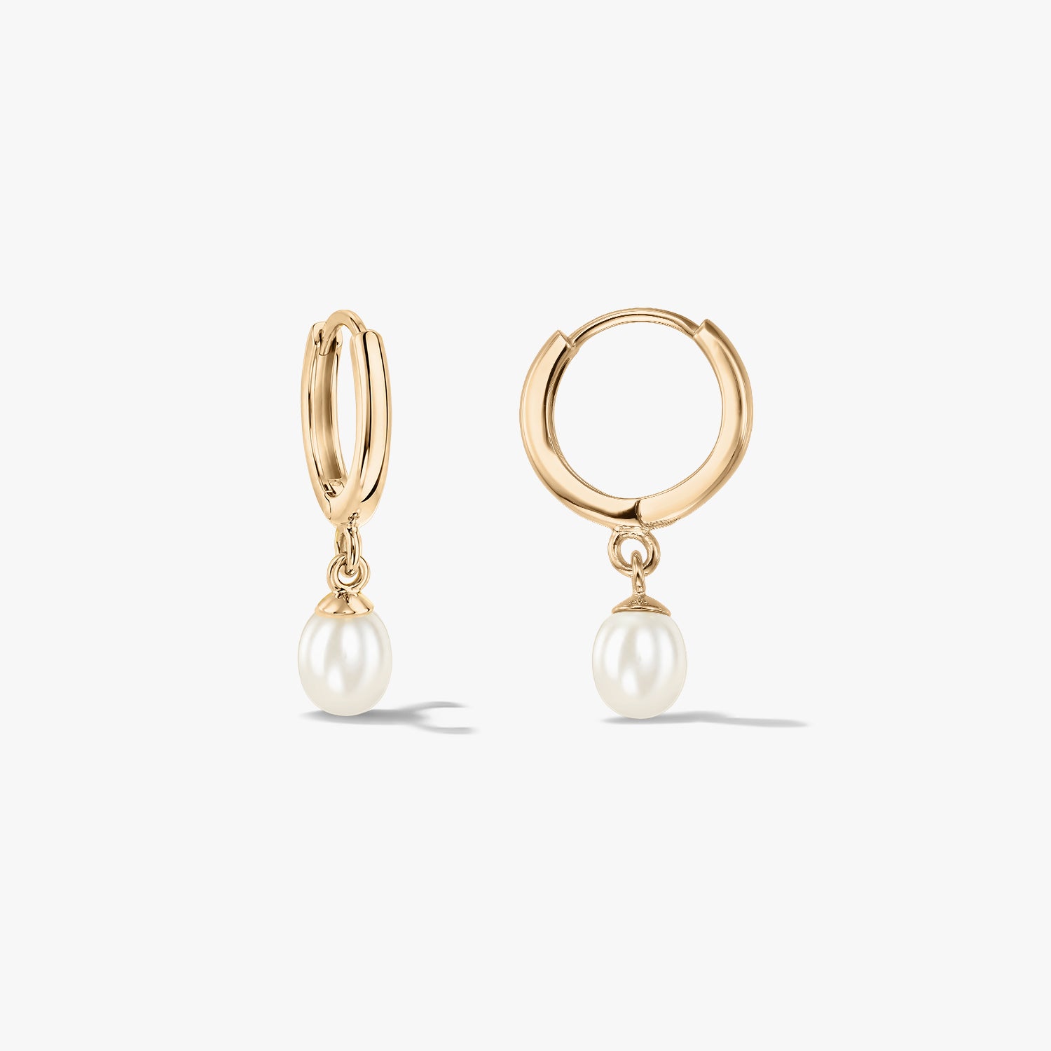 Paire de créoles élégantes en or jaune 14K ornées de perles naturelles, sur fond blanc.