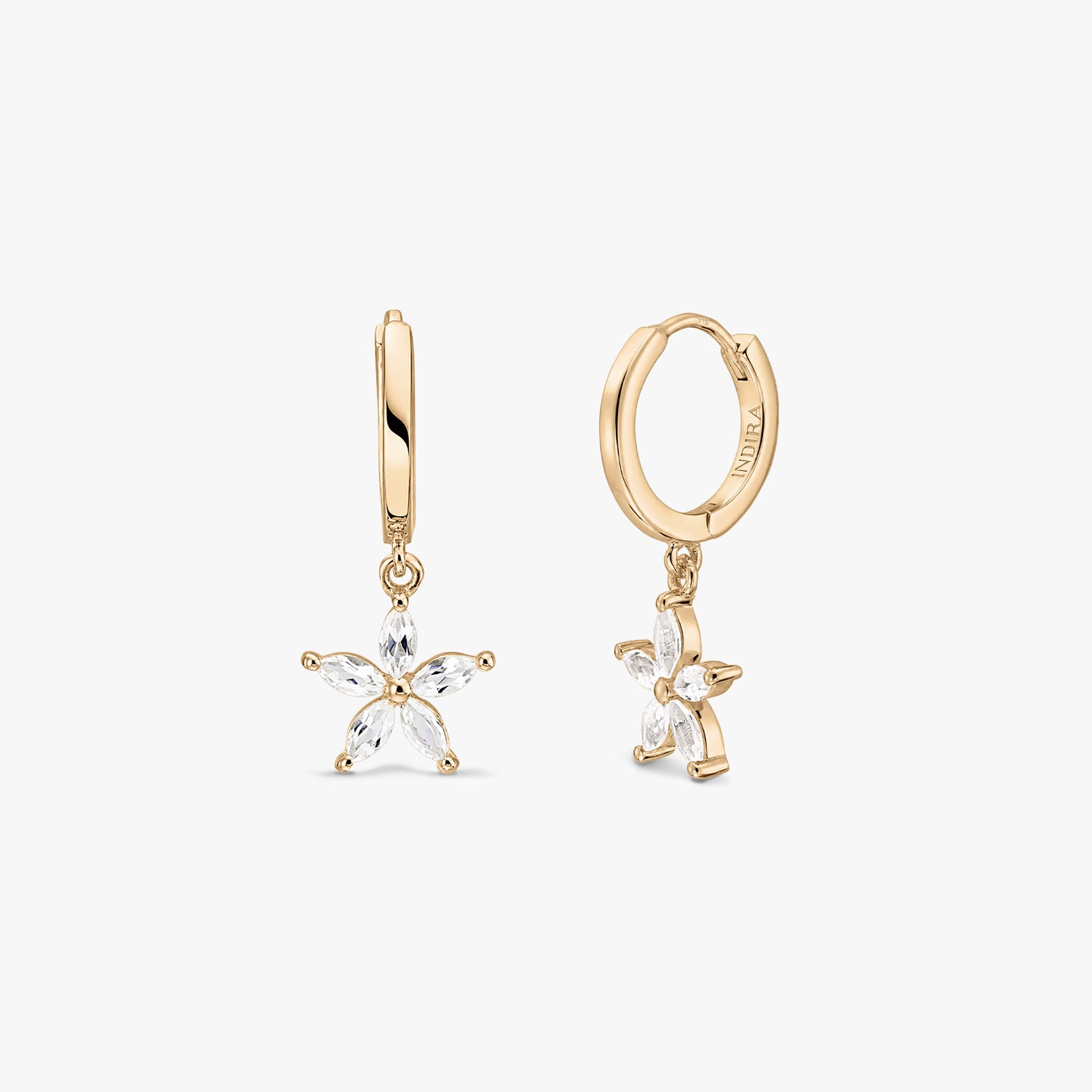 Boucles d’oreilles créoles huggie en argent sterling plaqué or, ornées de pendentifs en forme de fleur en topaze blanche, sur fond blanc.