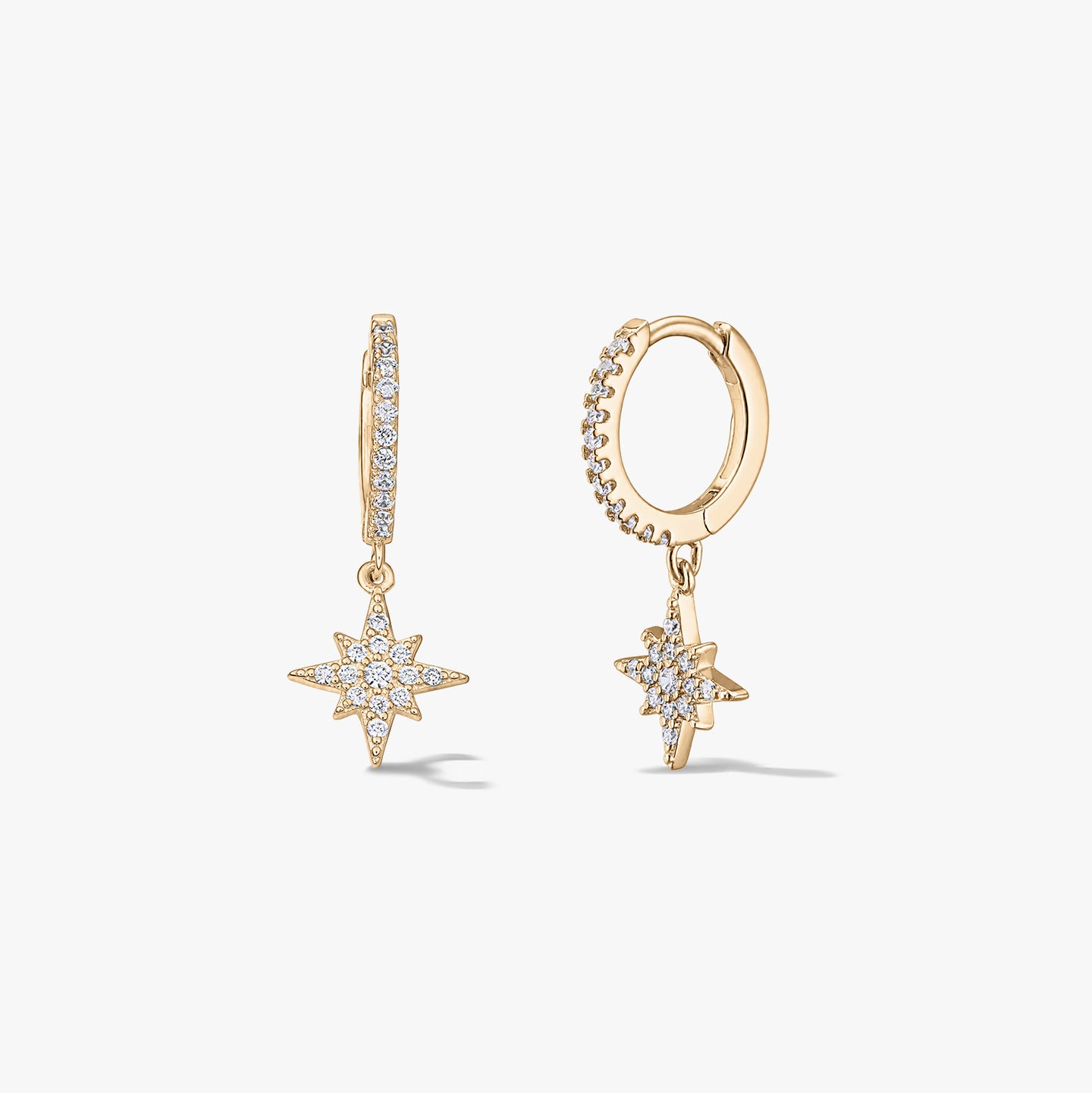 Paire de mini-créoles en argent plaqué or avec pendentifs étoile rayonnante pavés de zirconias, sur fond blanc.