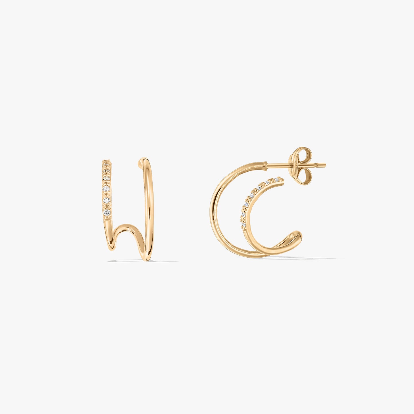 Paire de boucles d'oreilles à double anneau en or avec pierres incrustées sur fond blanc.