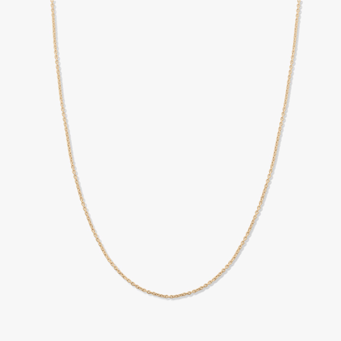 Collier chaîne en or jaune délicat à maillons fins, présenté sur fond blanc, sans pendentif.