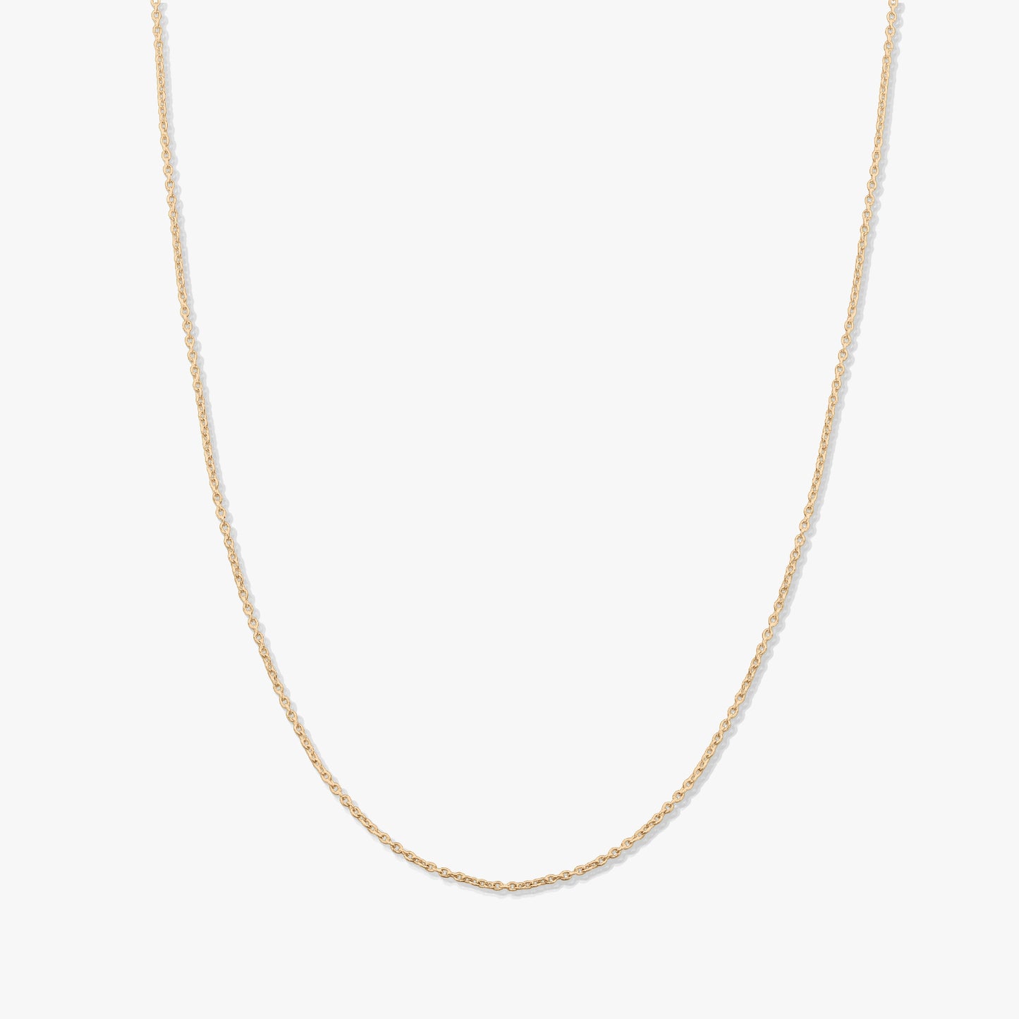 Collier chaîne en or jaune délicat à maillons fins, présenté sur fond blanc, sans pendentif.