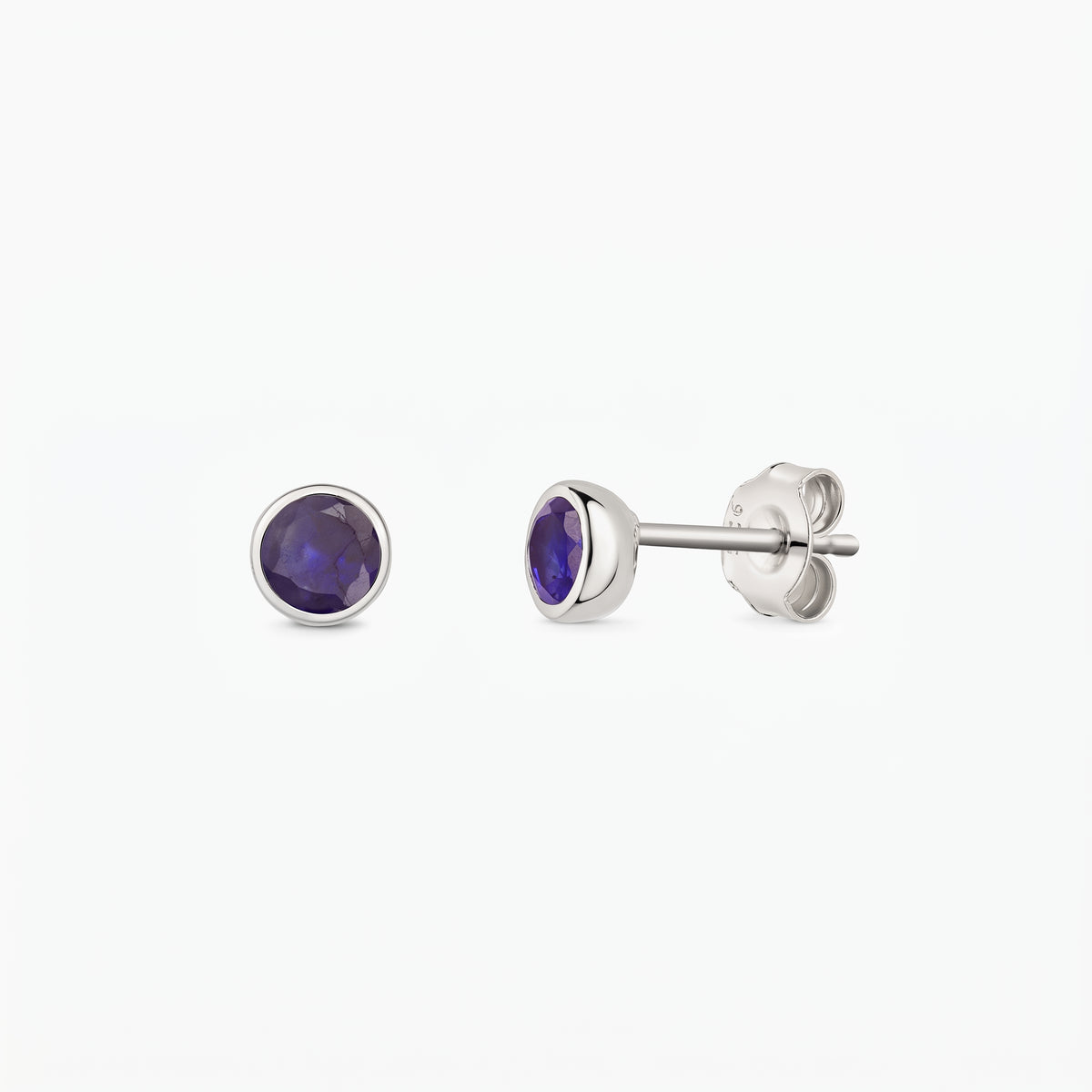 Puces d’oreilles en saphir serti clos en argent, vues de face et de profil sur fond blanc.
