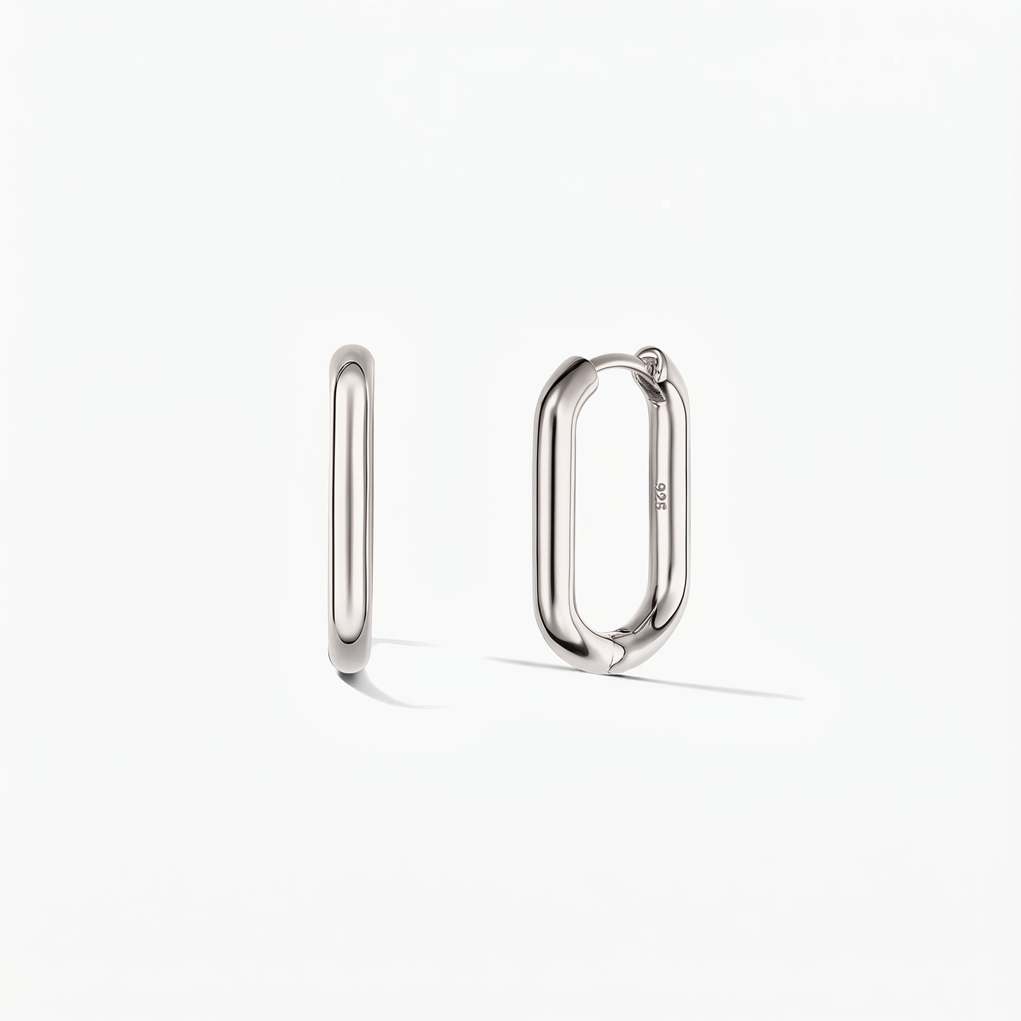 Paire de créoles carrées en argent sur fond blanc, l'une vue de côté et l'autre légèrement ouverte pour révéler le fermoir à charnière.