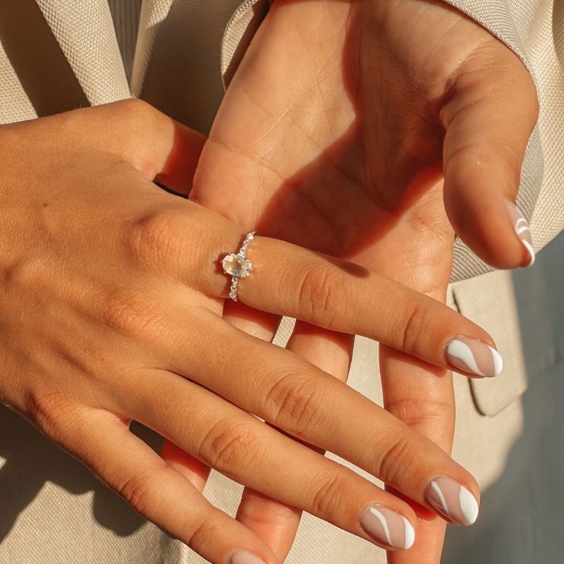 Mains montrant une Bague Selah en Argent avec une pierre de lune sur un fond doux.