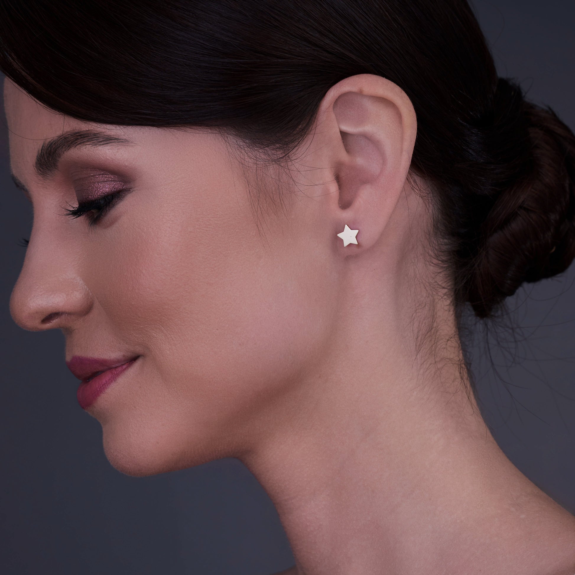 Vue de profil d'une femme portant des boucles d'oreilles en forme d'étoile en or 14K.