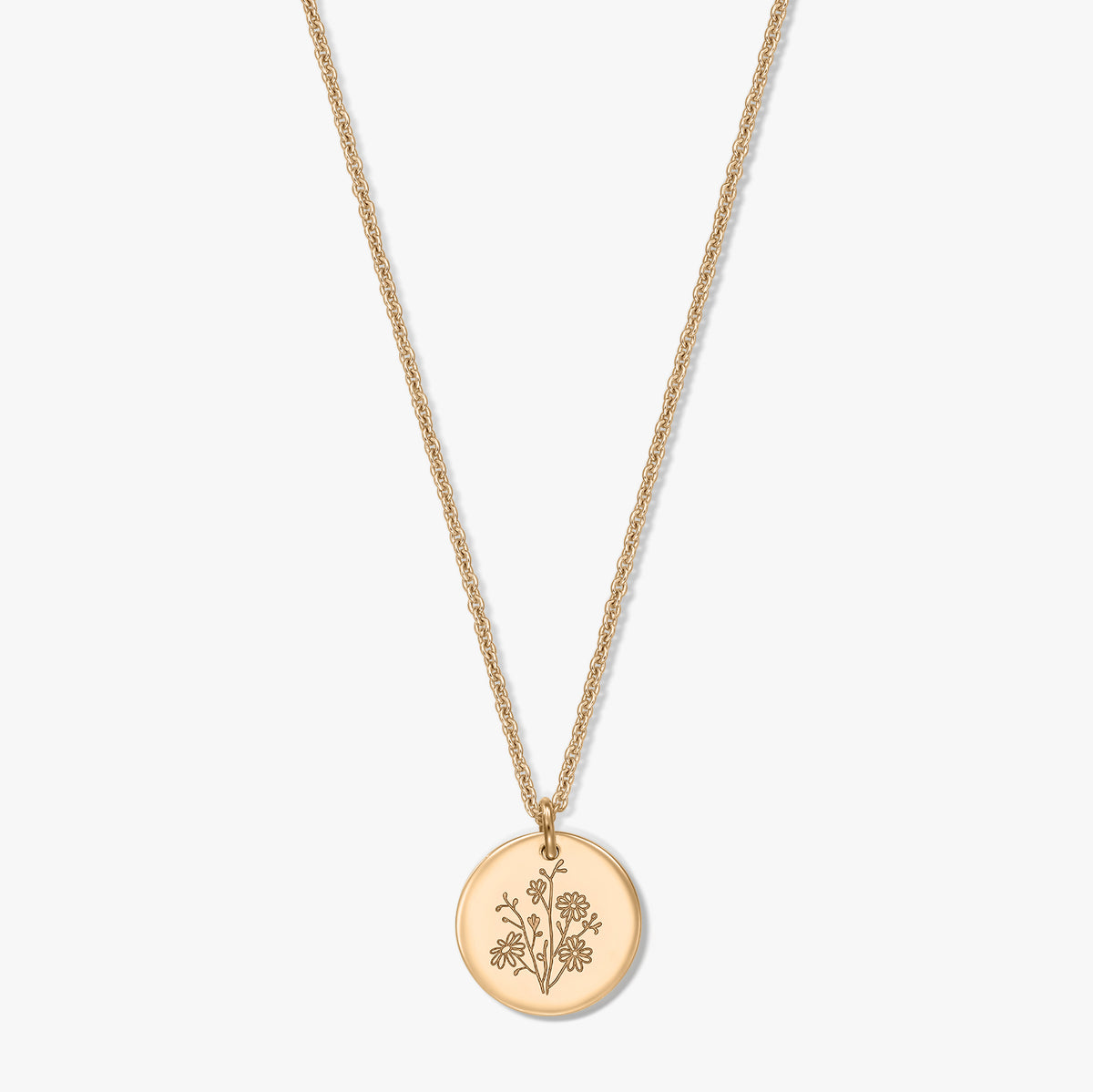 Collier en argent plaqué or avec une délicate chaîne corde et un pendentif rond façon pièce de monnaie, gravé d’une fleur de naissance, l’aster, isolé sur fond blanc.