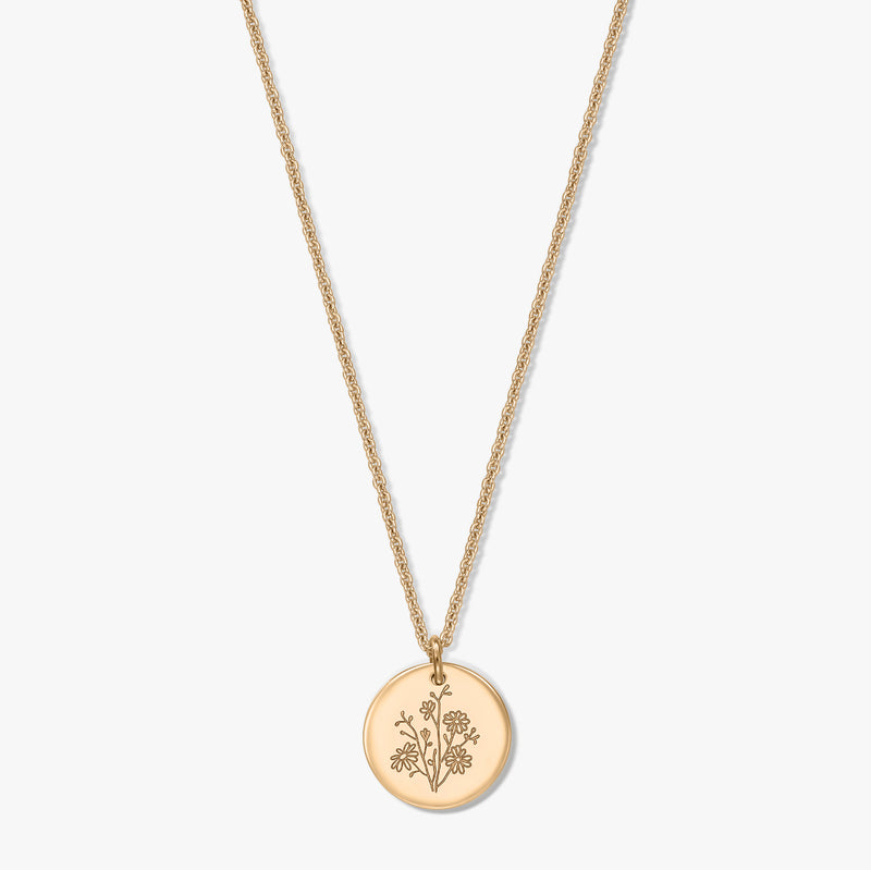 Collier en argent plaqué or avec une délicate chaîne corde et un pendentif rond façon pièce de monnaie, gravé d’une fleur de naissance, l’aster, isolé sur fond blanc.