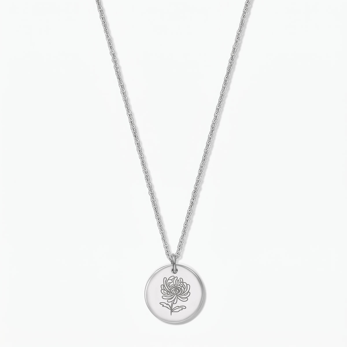 Collier fleur de naissance en argent sterling avec pendentif disque rond gravé d’un chrysanthème, sur chaîne fine, photographié sur fond blanc.