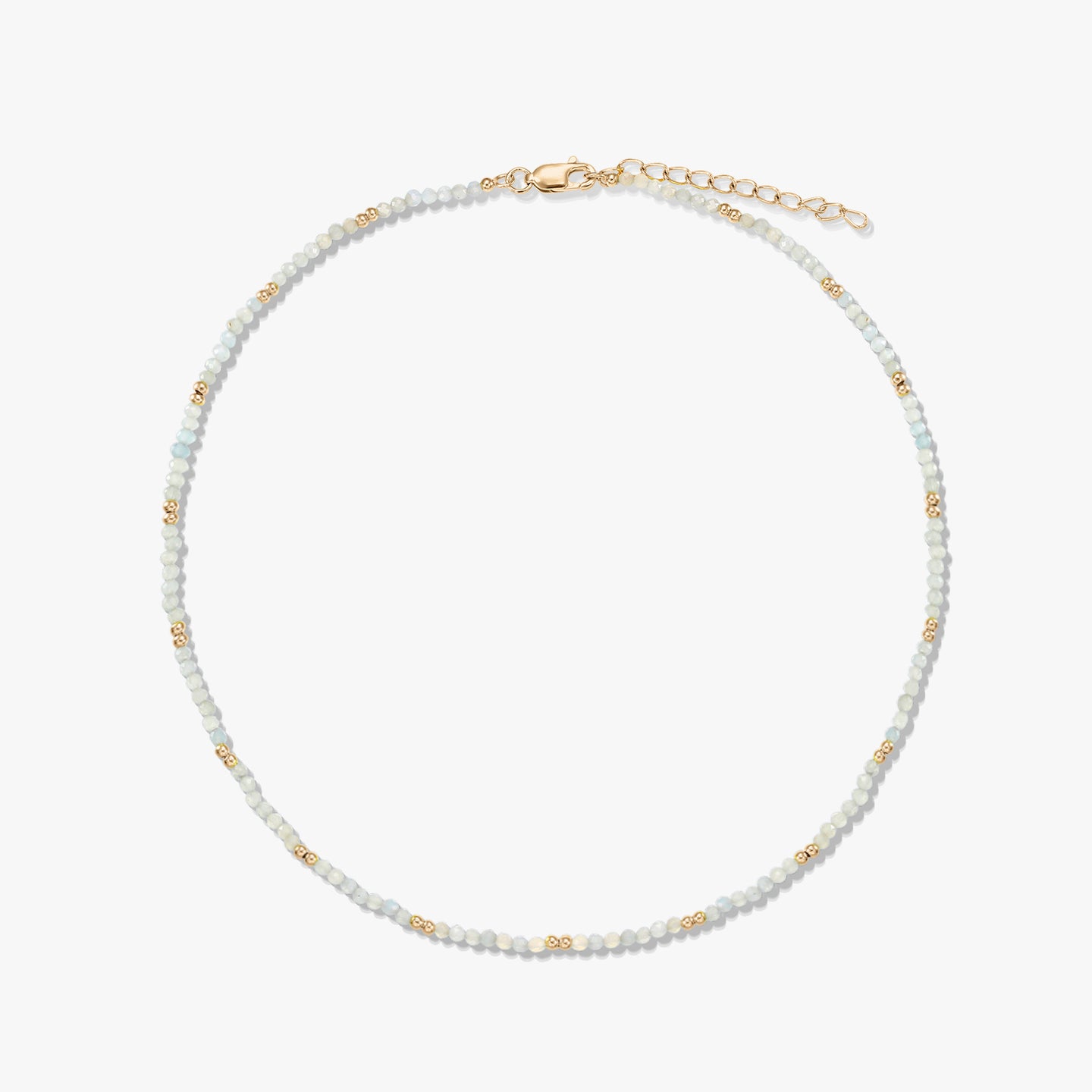 Collier délicat en perles de pierre de lune, rehaussé de petites perles intercalaires dorées, avec fermoir mousqueton et chaînette d’extension en argent sterling plaqué or, disposé en cercle sur fond blanc.