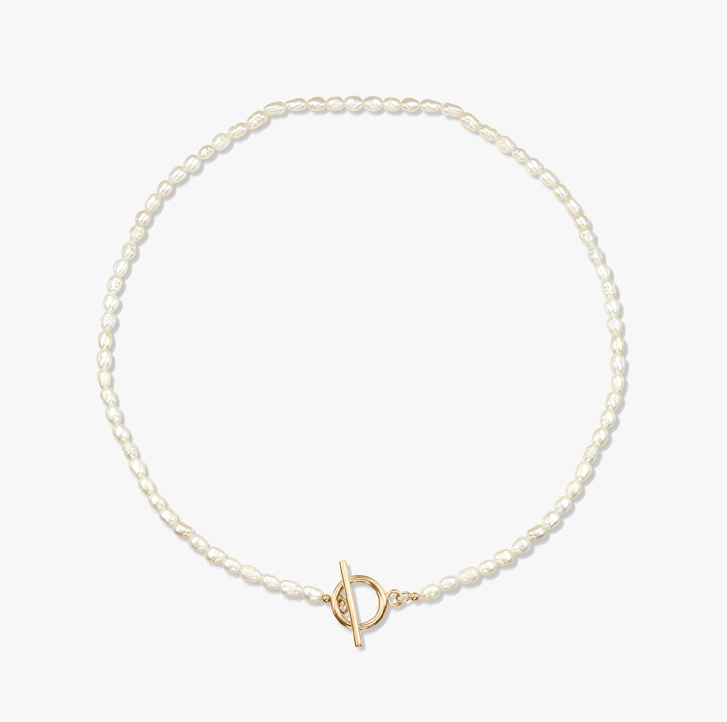 Un collier de perles minimaliste avec un fermoir toggle en or sur fond blanc.