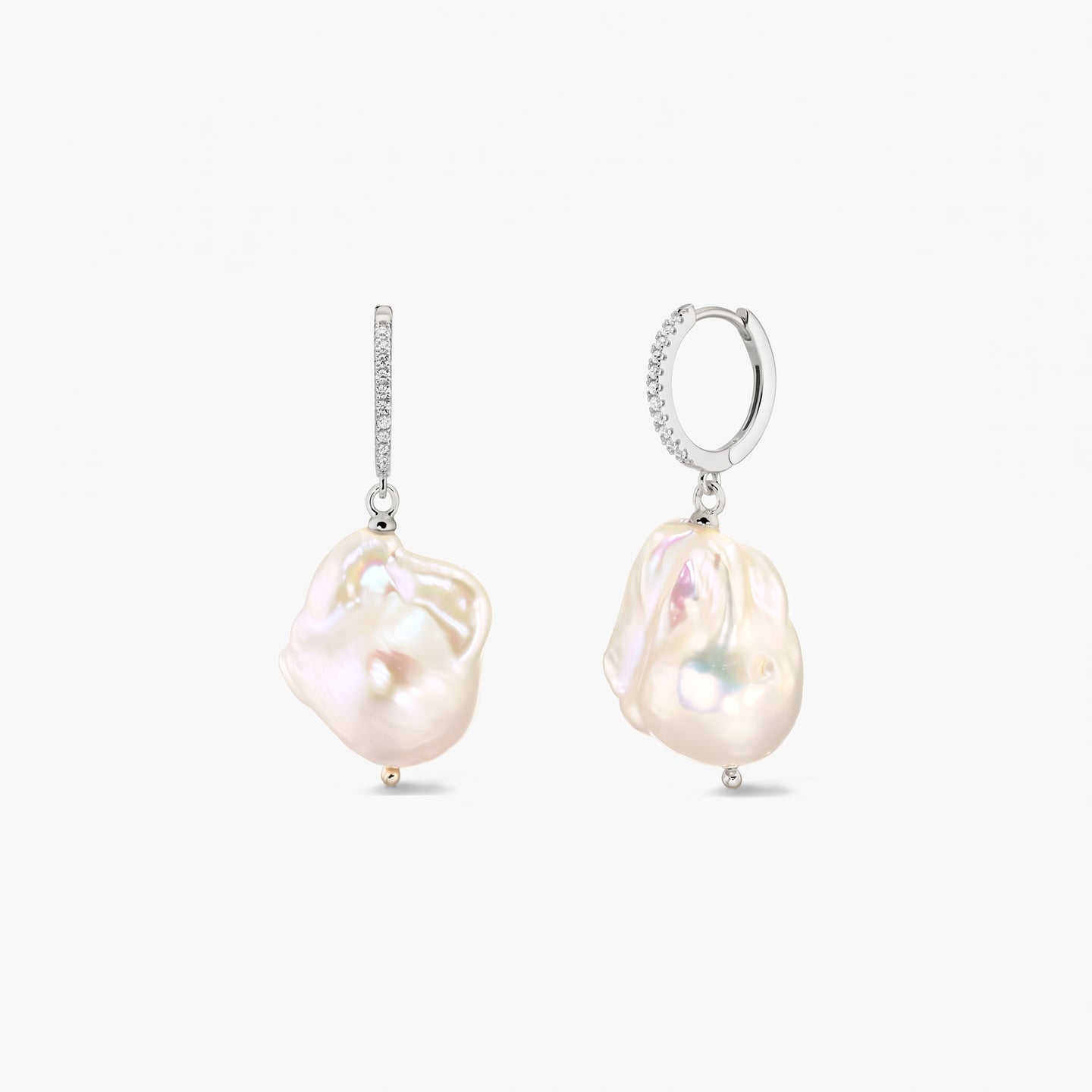 Paire de créoles en argent 925 rhodié, serties de zirconias en pavé et ornées de grandes perles baroques organiques, sur fond blanc.