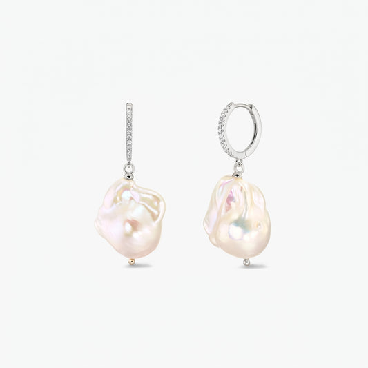 Paire de créoles en argent 925 rhodié, serties de zirconias en pavé et ornées de grandes perles baroques organiques, sur fond blanc.