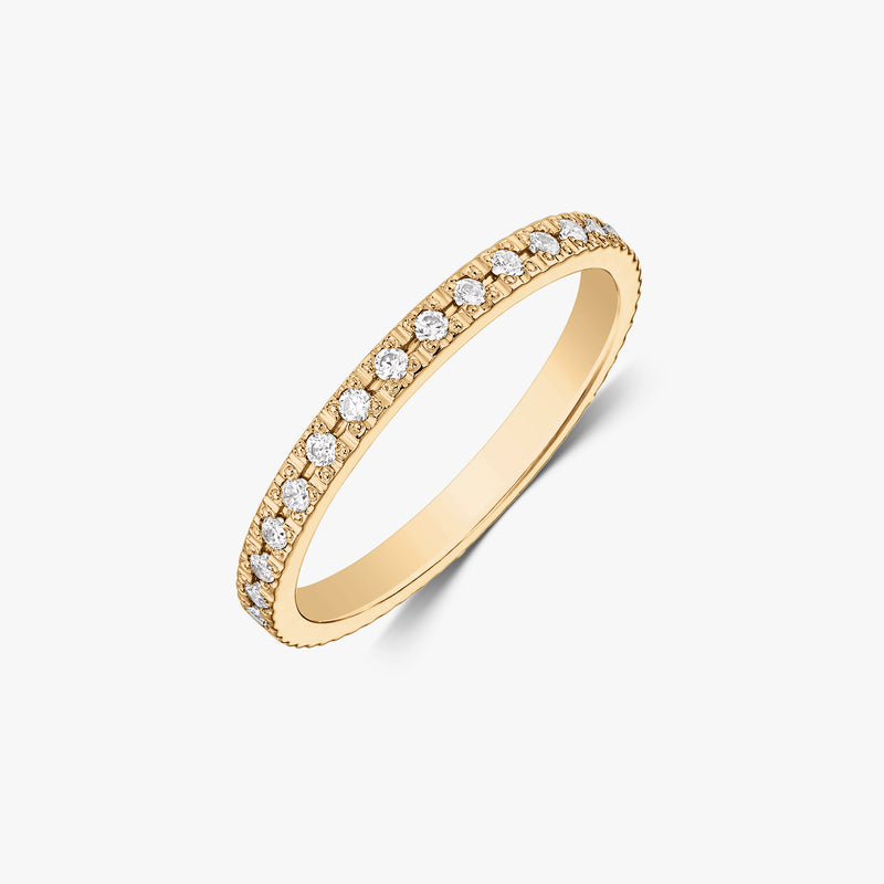 Élégante alliance rivière en or jaune 14K sertie de pierres rondes blanches en zircone, photographiée sur fond blanc.