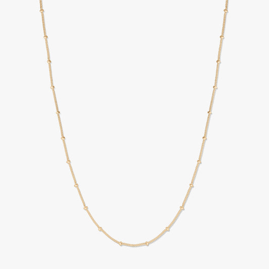 Collier chaîne en argent plaqué or, présenté sur fond blanc, formant une douce forme en U avec de petites perles espacées le long de la chaîne.