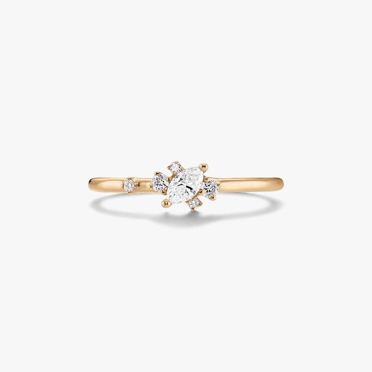 Bague fine en or jaune 14K ornée d’un diamant central taille marquise et de petits diamants d’accent ronds, sur fond blanc.