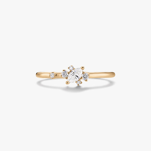 Bague fine en or jaune 14K ornée d’un diamant central taille marquise et de petits diamants d’accent ronds, sur fond blanc.