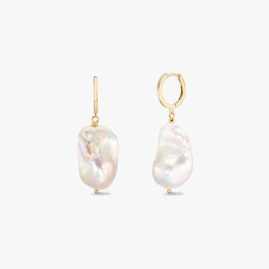 Paire de créoles plaquées or ornées de perles blanches baroques à l'allure organique sur fond blanc.