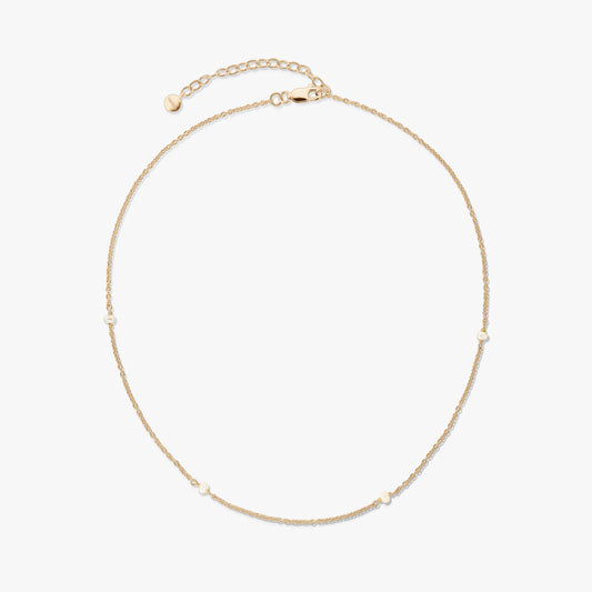 Collier délicat en argent 925 plaqué or avec de petites perles naturelles et une rallonge réglable avec fermoir mousqueton, sur fond blanc.