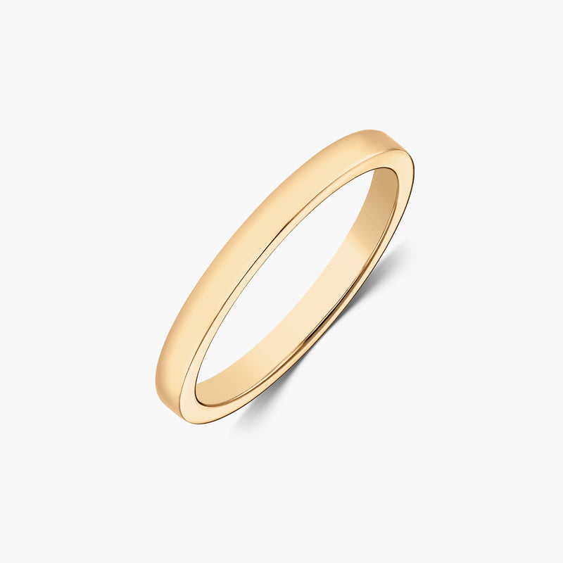 Prise de vue en studio, en angle, d’une bague jonc fine en or jaune 14 carats polie sur fond blanc.