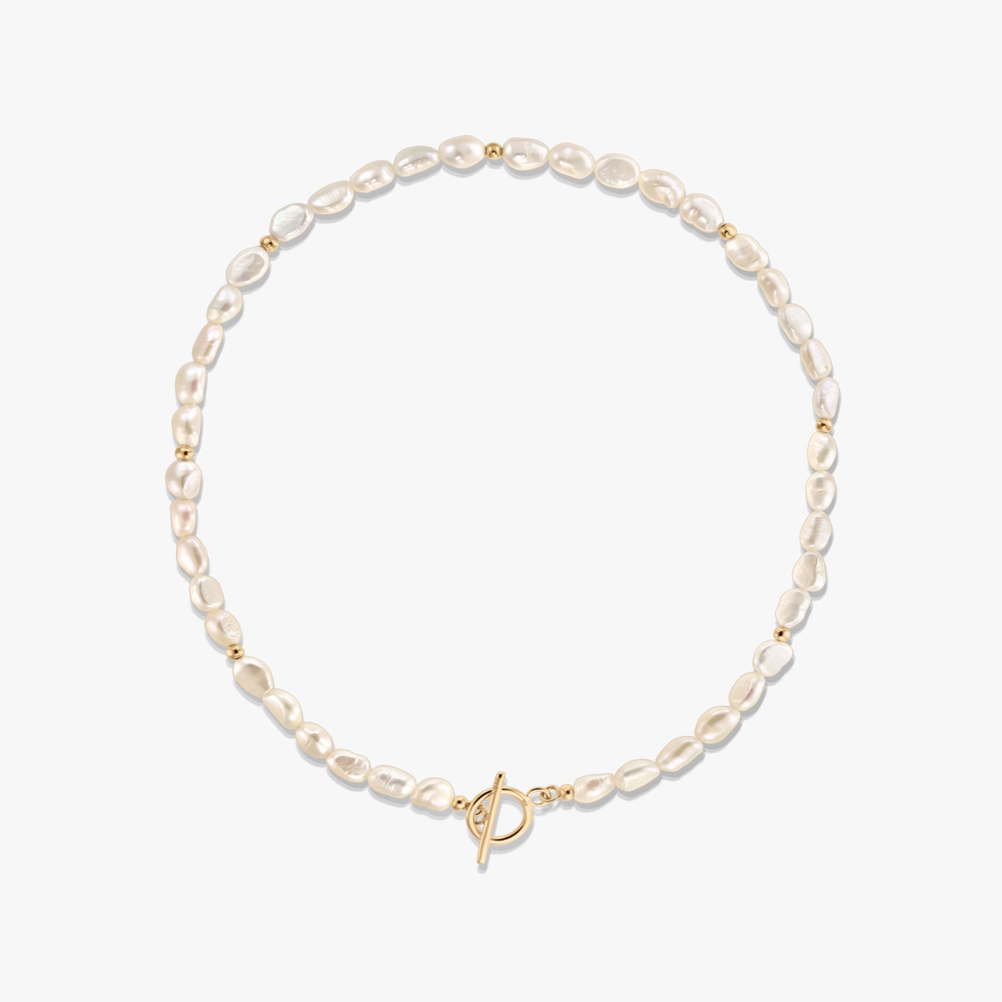 Photo en studio d’un collier de perles naturelles avec de petites perles intercalaires dorées et un fermoir toggle ton doré, disposé en cercle sur fond blanc.