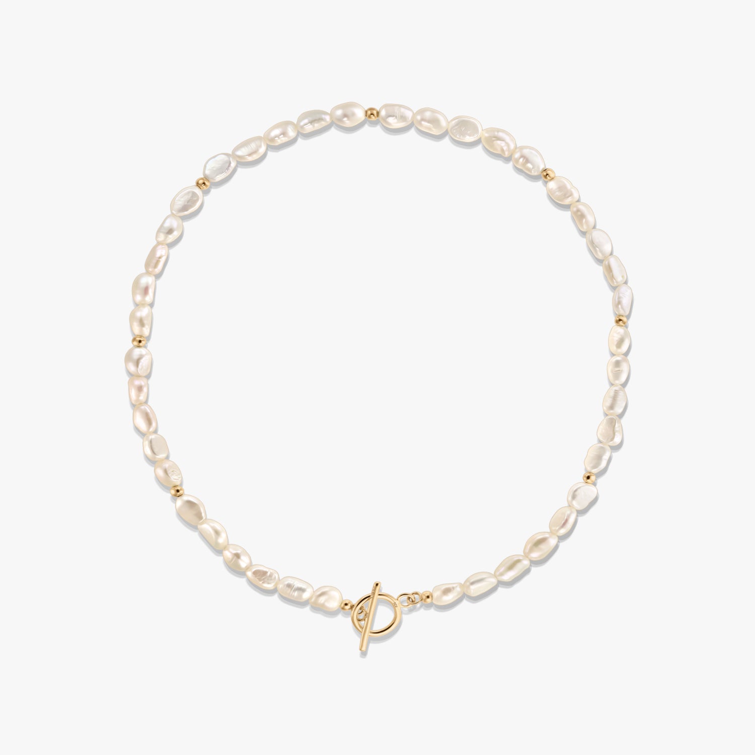 Photo en studio d’un collier de perles naturelles avec de petites perles intercalaires dorées et un fermoir toggle ton doré, disposé en cercle sur fond blanc.