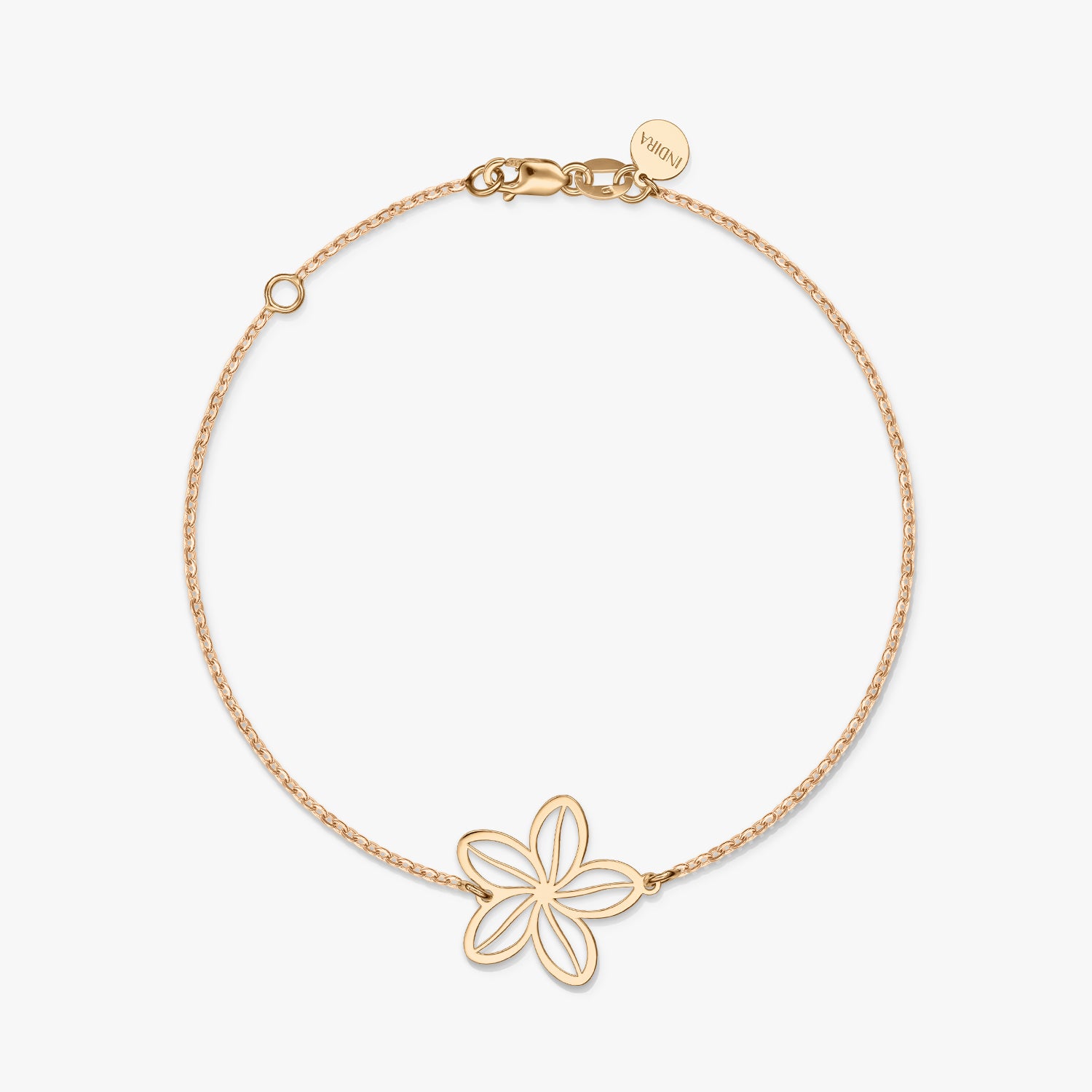 Un bracelet minimaliste en or avec un charm fleur délicat sur un fond blanc uni.