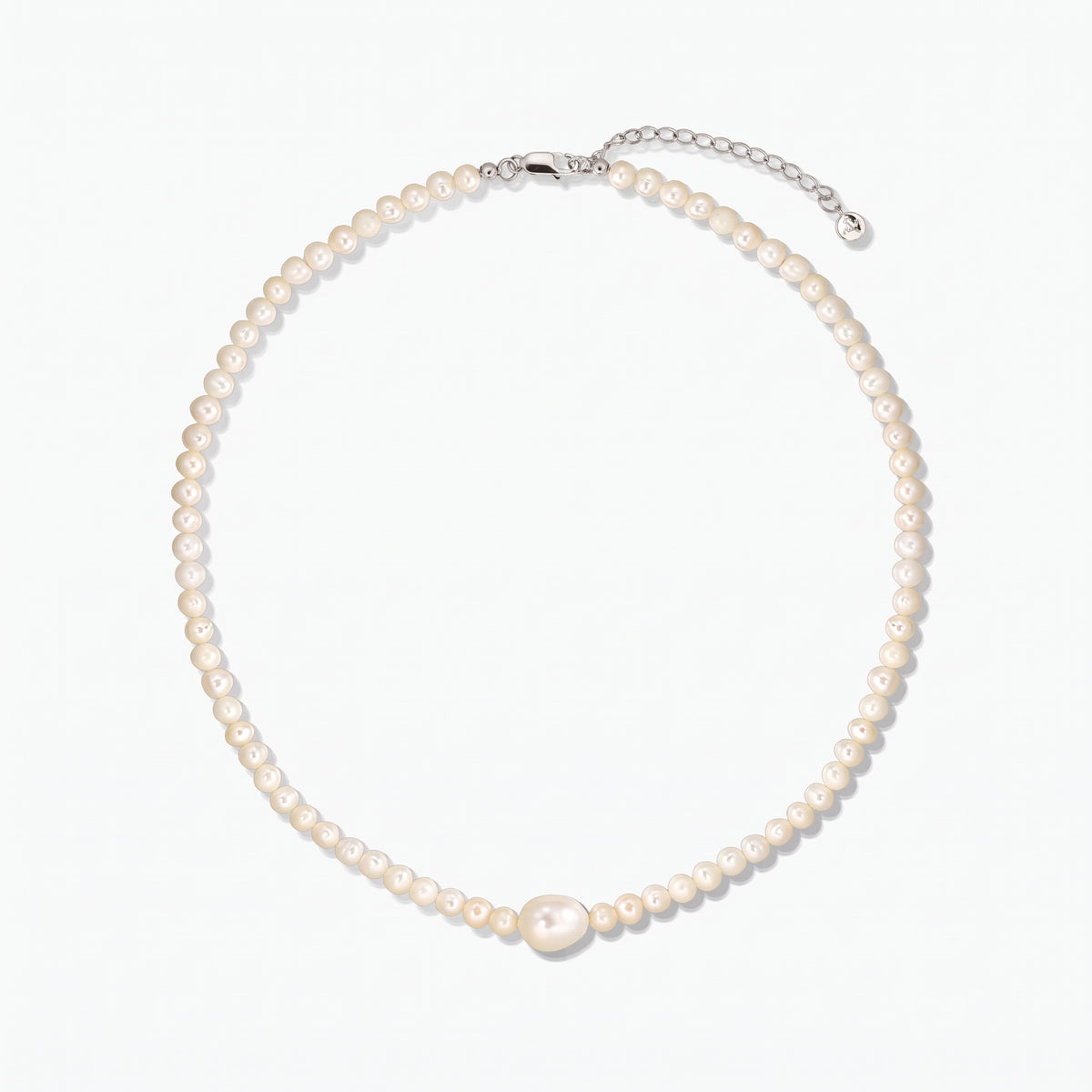 Collier de perles de culture avec une perle centrale plus grande et un fermoir en argent avec rallonge, photographié sur fond blanc.