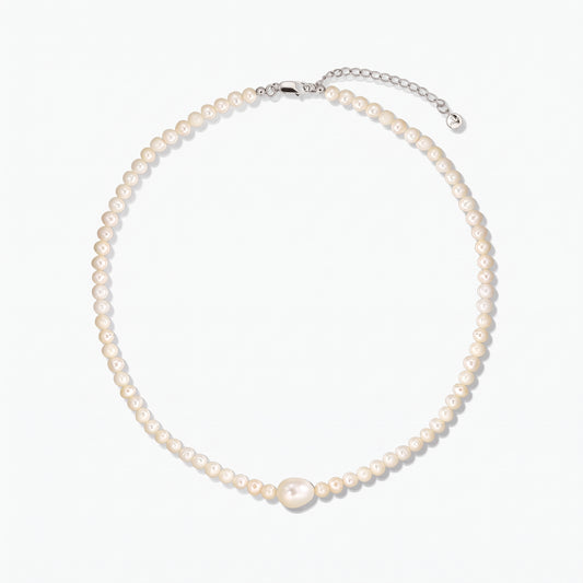 Collier de perles de culture avec une perle centrale plus grande et un fermoir en argent avec rallonge, photographié sur fond blanc.
