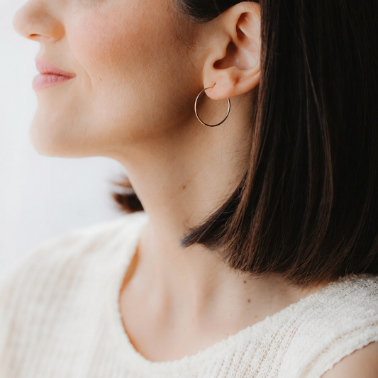 Gros plan sur l’oreille d’un modèle portant une mini-créole en or jaune 14K, dans une douce lumière naturelle.