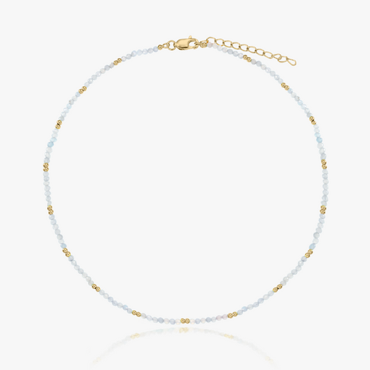 Collier délicat en perles de pierre de lune, rehaussé de fins accents dorés et doté d’un fermoir plaqué or réglable, présenté sur fond blanc.