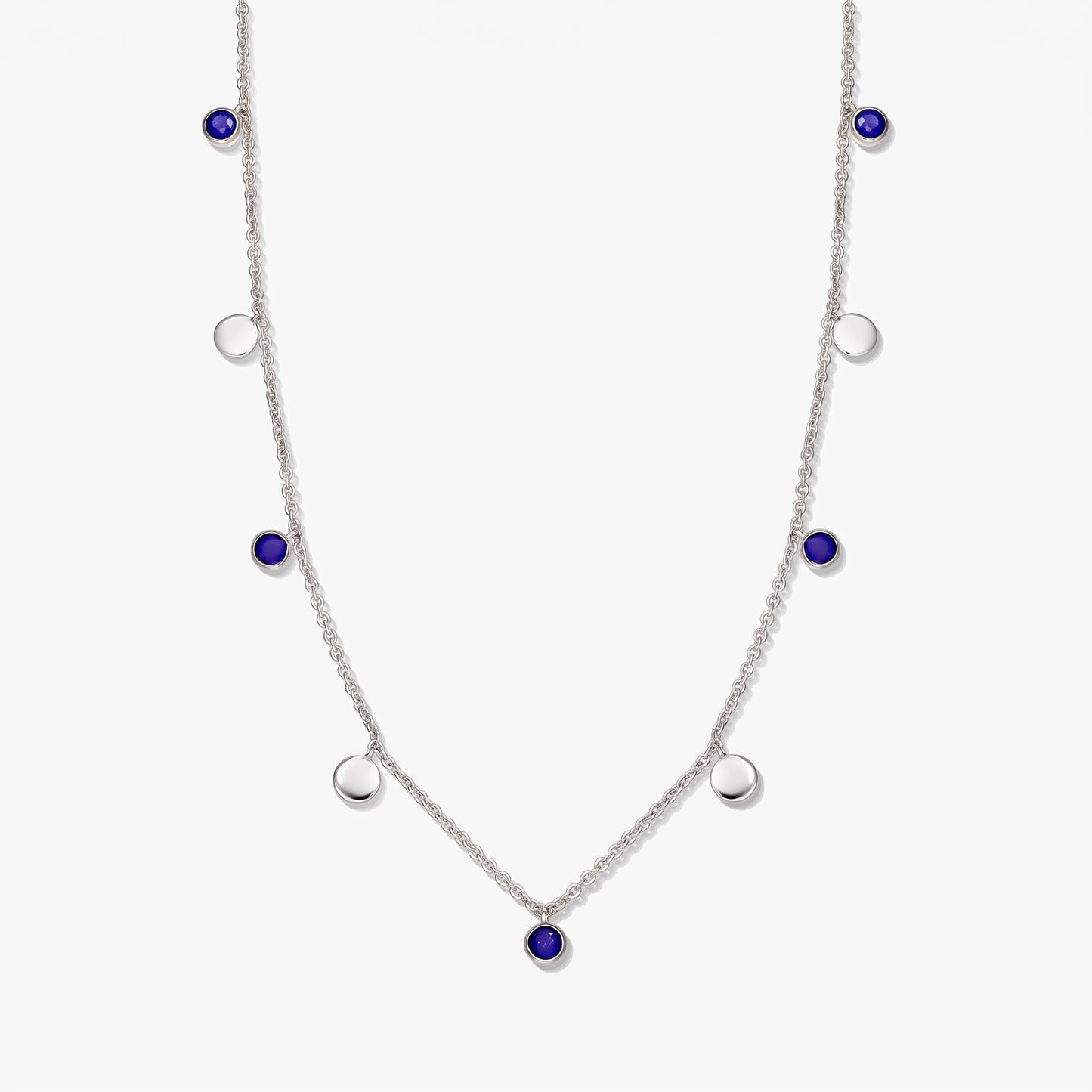 Collier à stations en argent sterling avec cabochons ronds en lapis-lazuli et pastilles en argent poli sur fond blanc.
