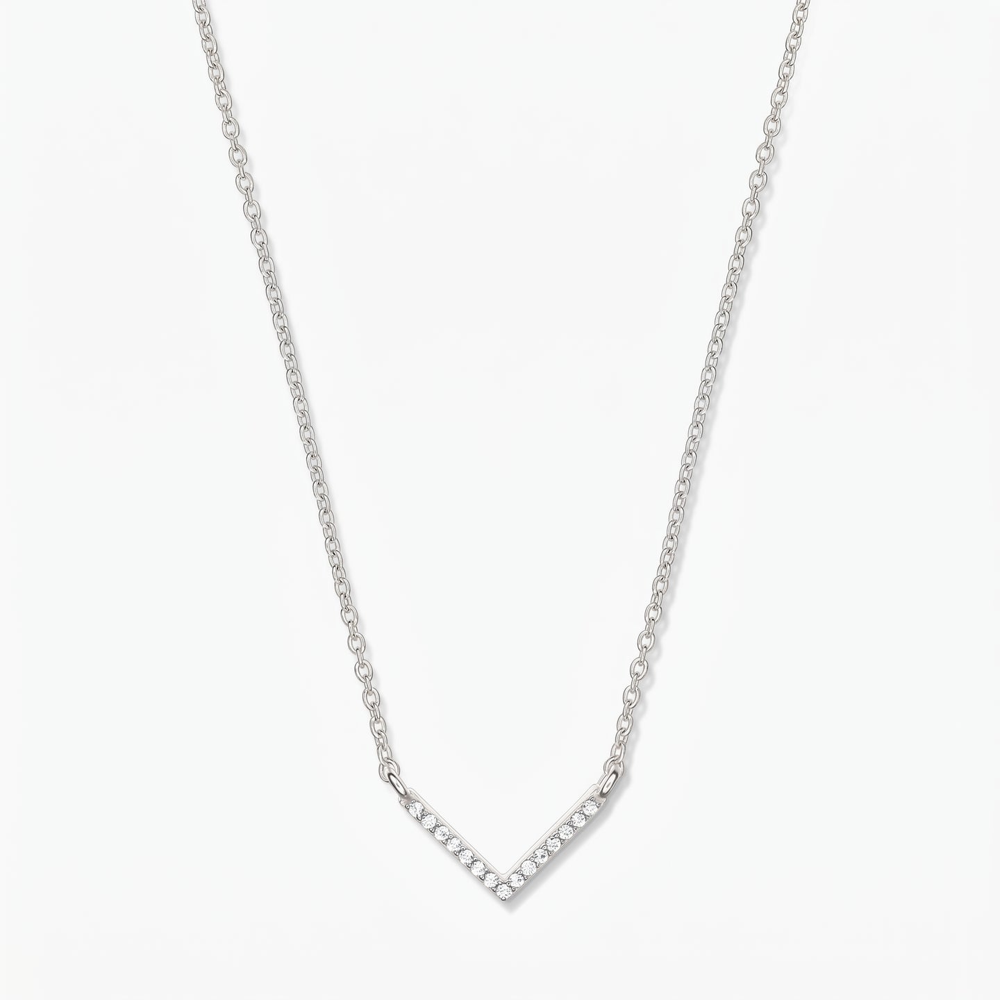 Collier en argent en forme de V avec chaîne délicate et pendentif chevron pavé d’oxydes de zirconium, sur fond blanc.