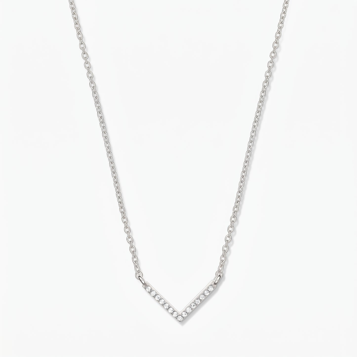 Collier en argent en forme de V avec chaîne délicate et pendentif chevron pavé d’oxydes de zirconium, sur fond blanc.
